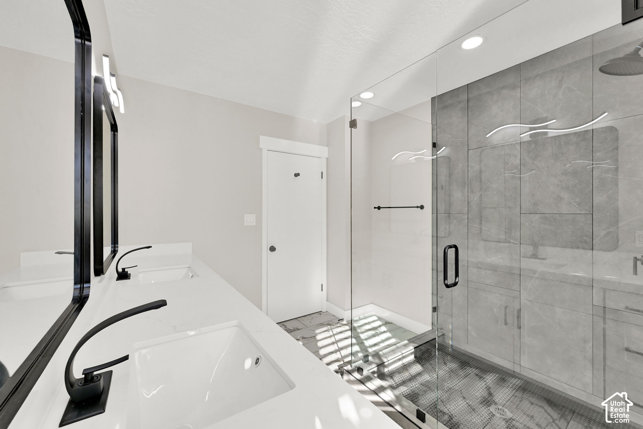 Modern bathroom with a white double-sink vanity, black faucets, and a glass walk-in shower.