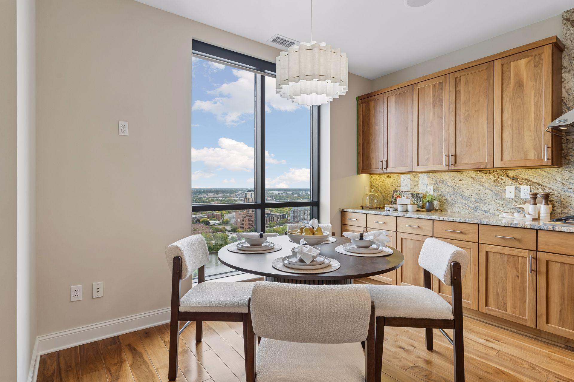 Dining area with a set round table, wood cabinetry, and large city-view window.