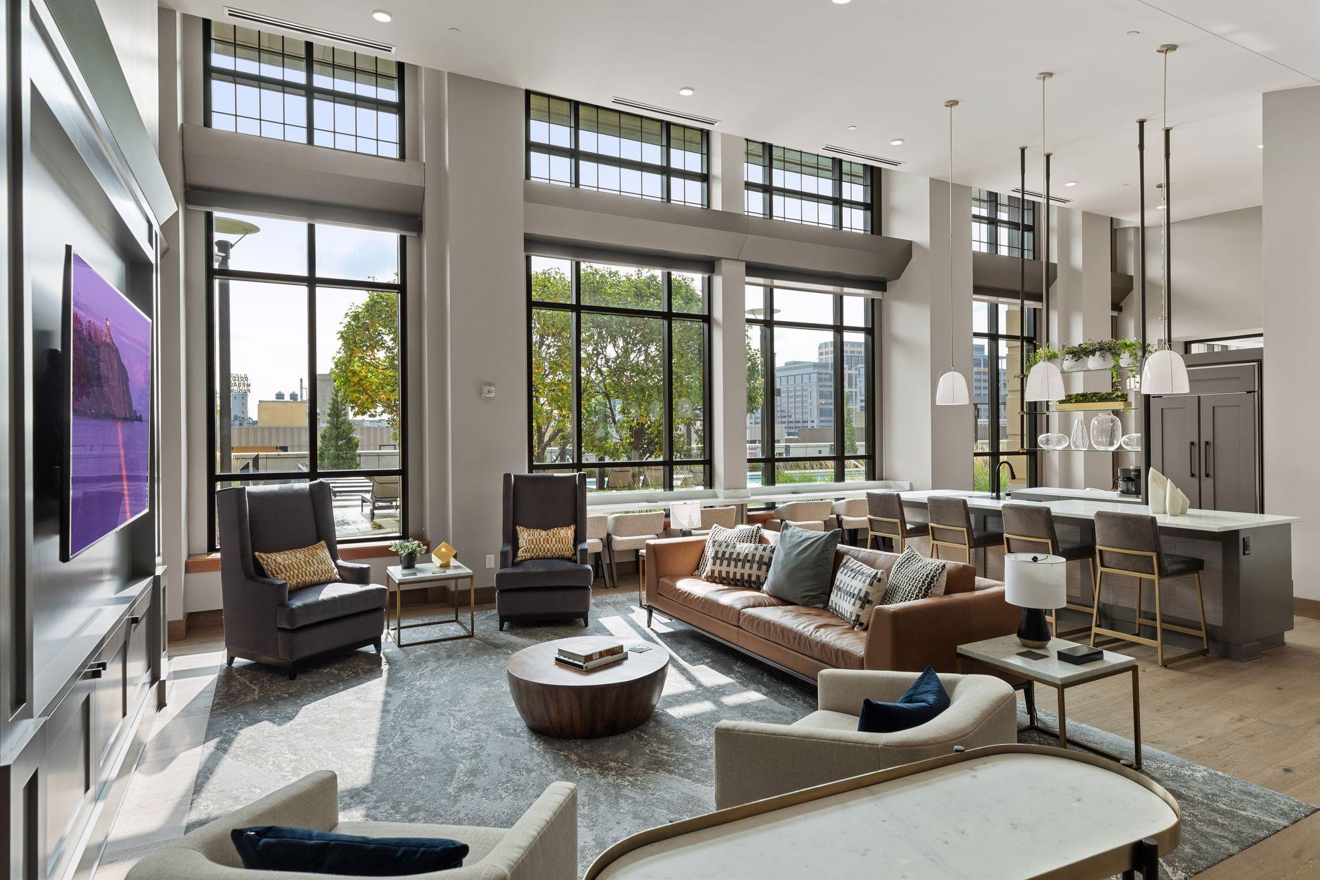 Open-plan condo living room with floor-to-ceiling windows, high ceilings, and a kitchen island with bar seating.