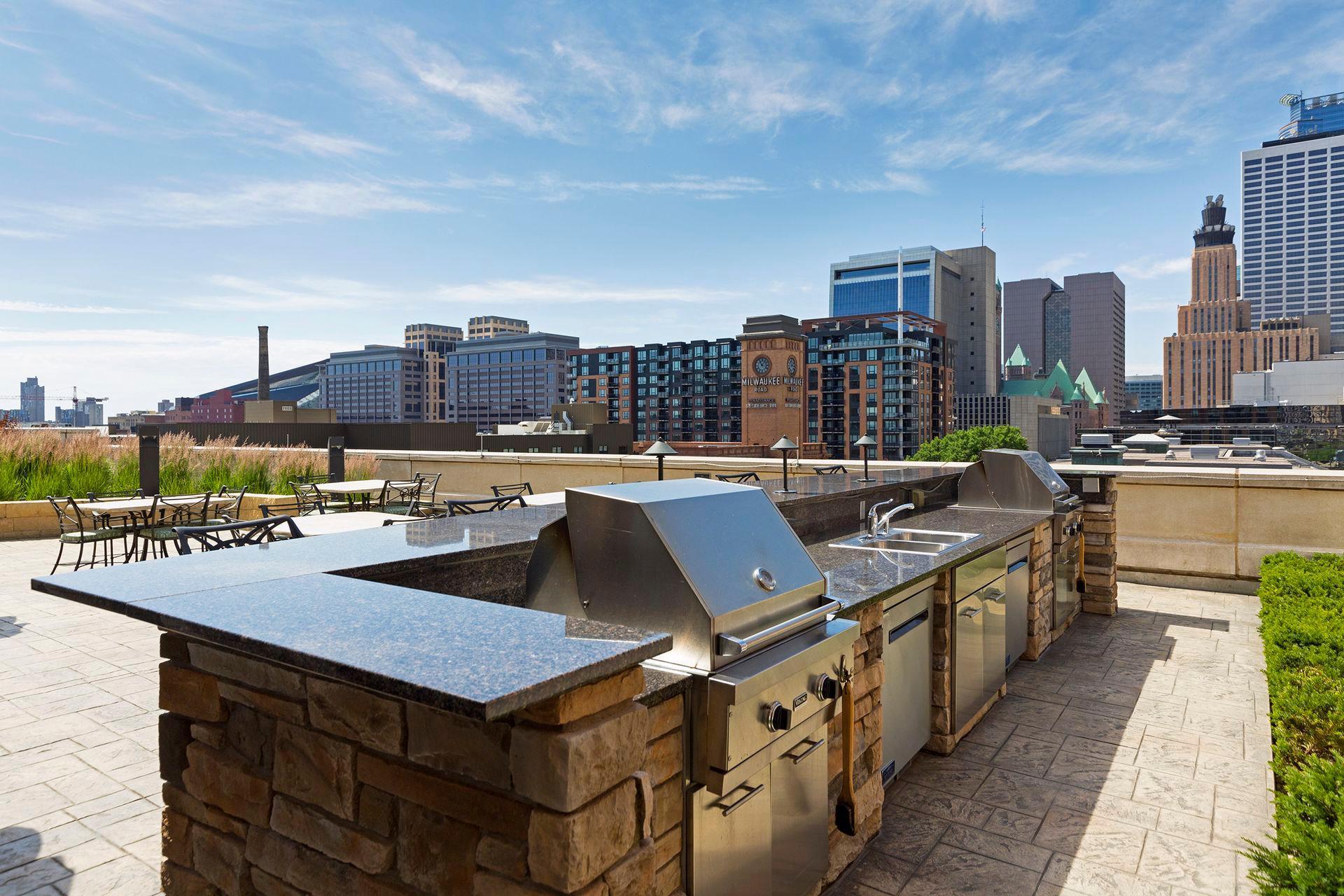 Rooftop grilling area with stone counters, patio seating, and Minneapolis skyline views.