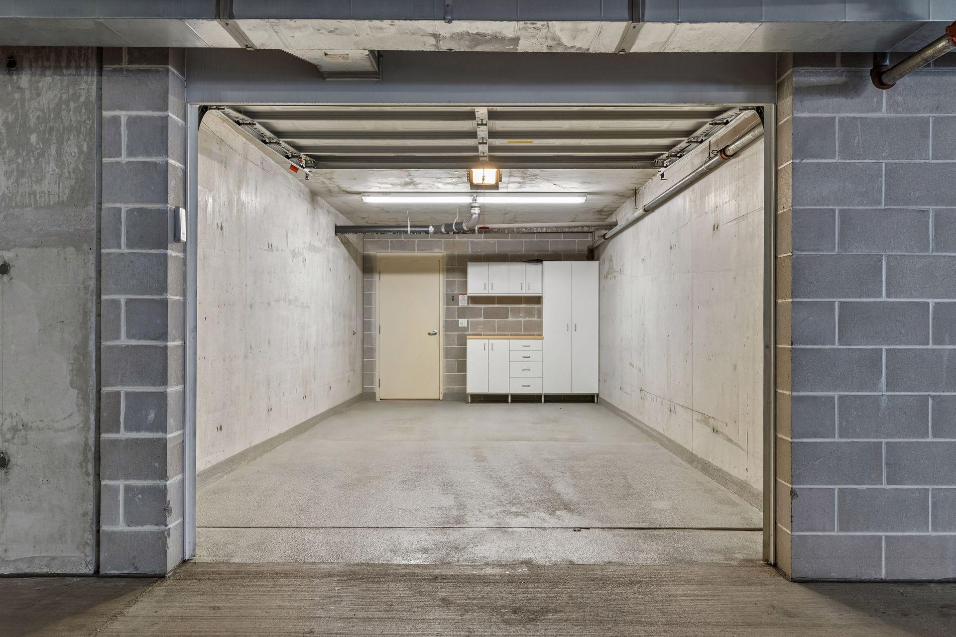 Empty concrete parking garage stall with white storage cabinets at the back.