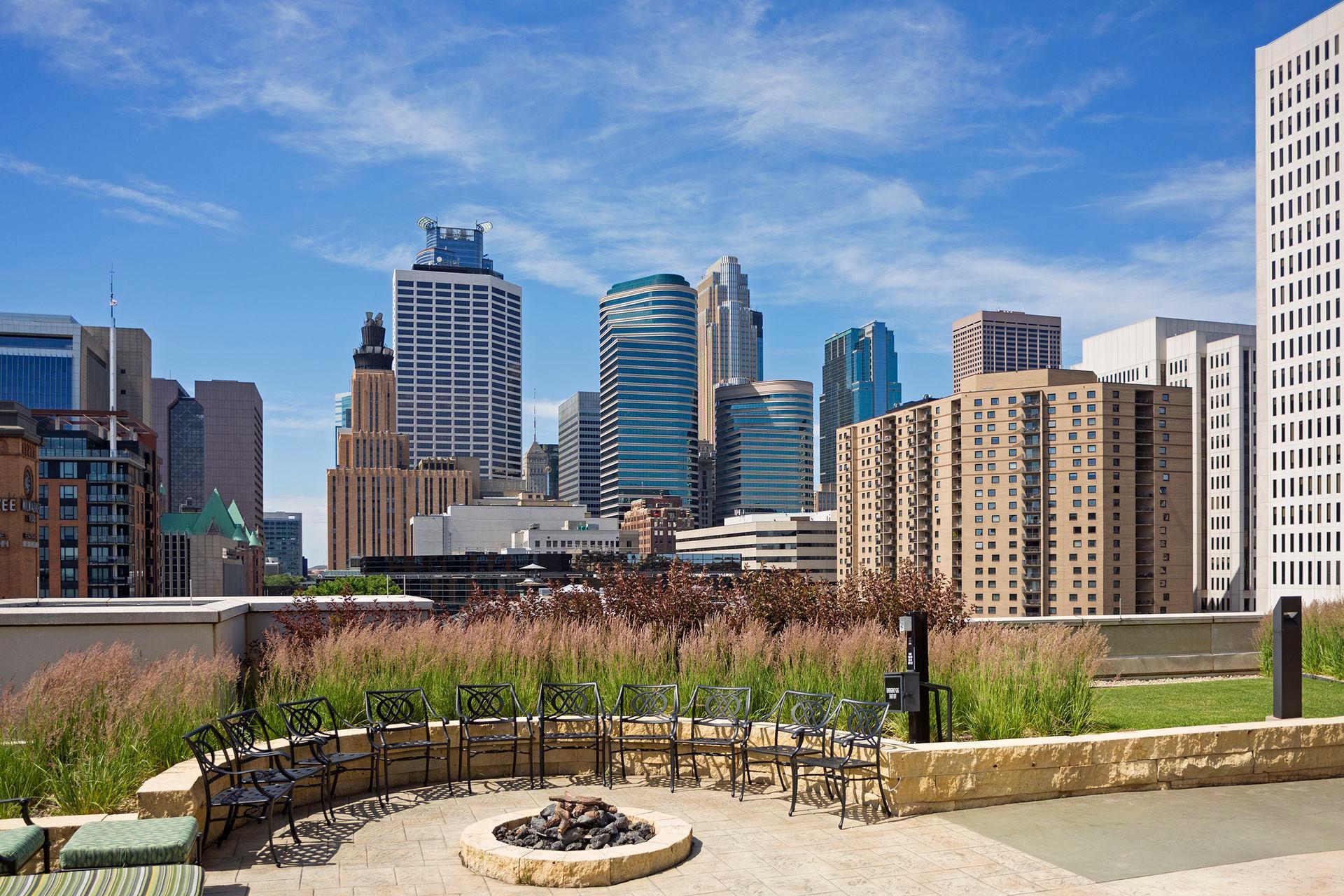 Rooftop terrace with a stone fire pit and seating overlooking the Minneapolis skyline.