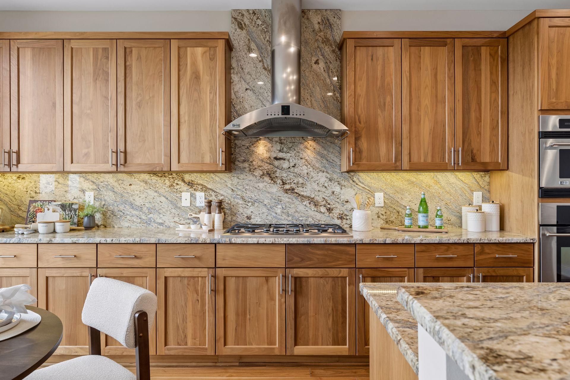 Kitchen with warm wood cabinetry, granite counters and backsplash, gas cooktop, and stainless steel range hood.