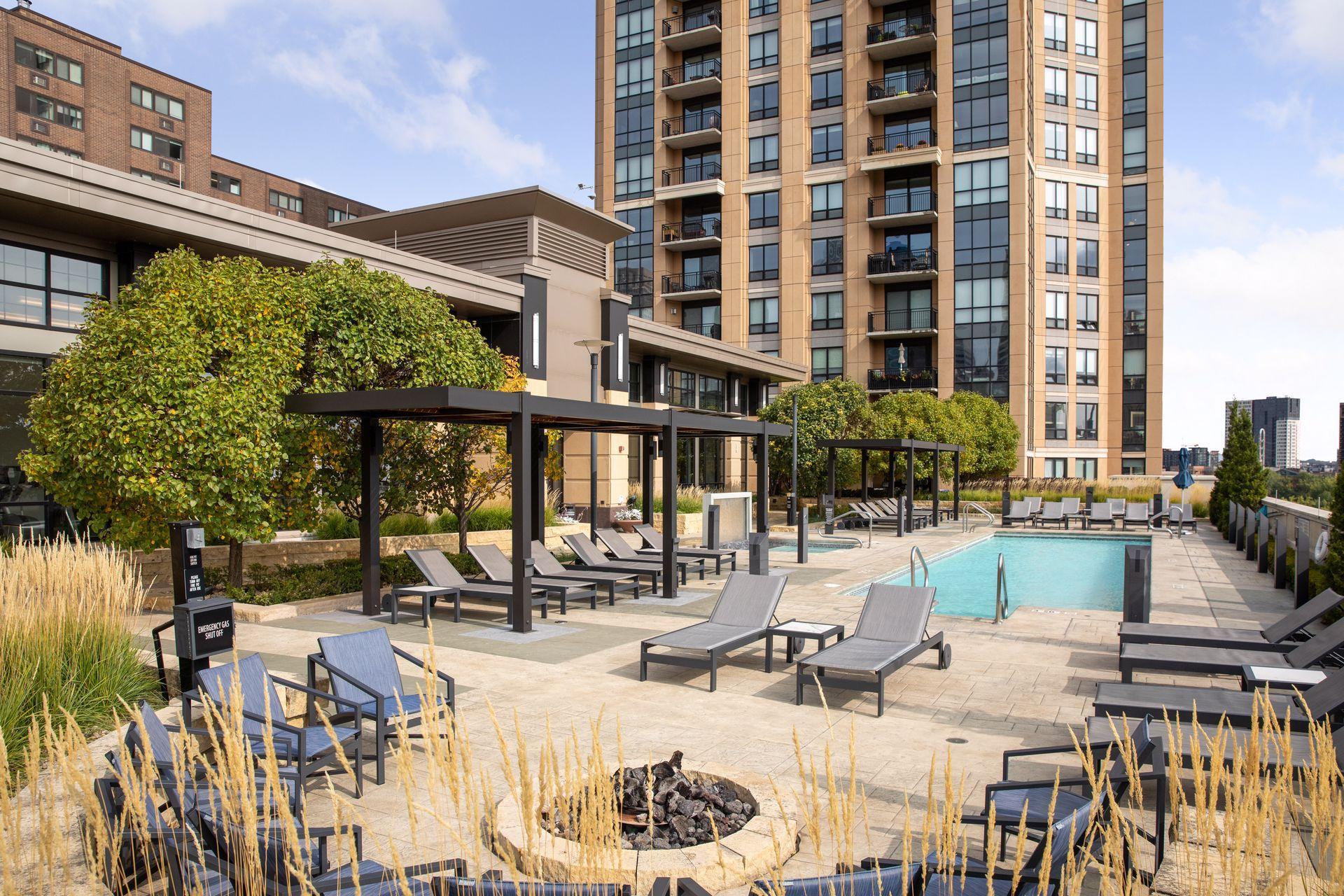 Condominium pool deck with lounge chairs, pergolas, and landscaped seating areas.
