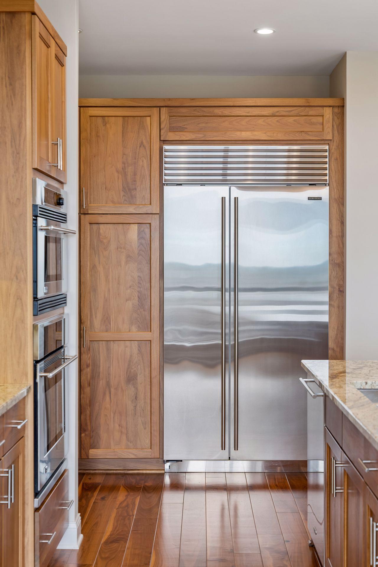 Kitchen with a stainless-steel refrigerator, warm wood cabinetry, and built-in ovens.