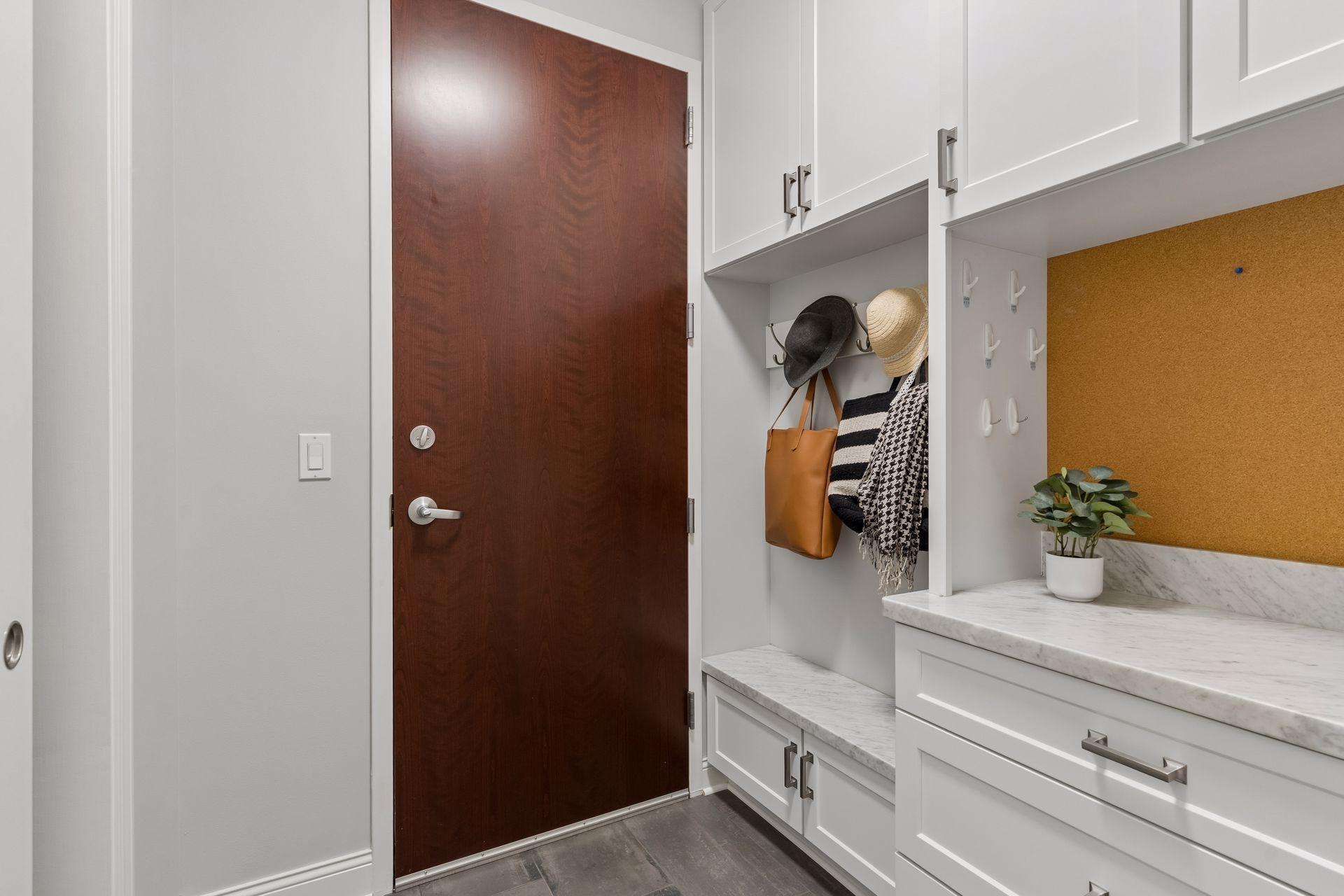 Condo entryway with white built-in storage, marble counter, and a dark wood front door.