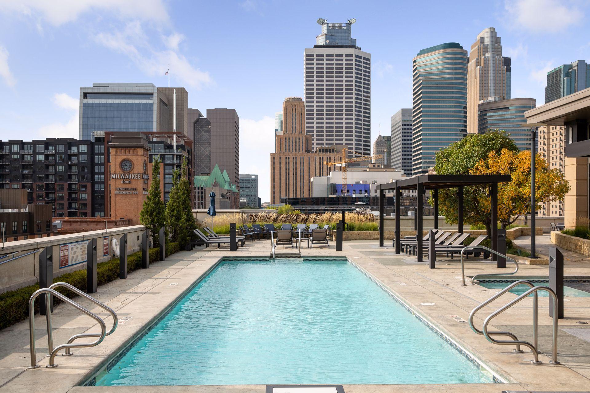 Rooftop pool and lounge deck overlooking downtown Minneapolis skyscrapers.