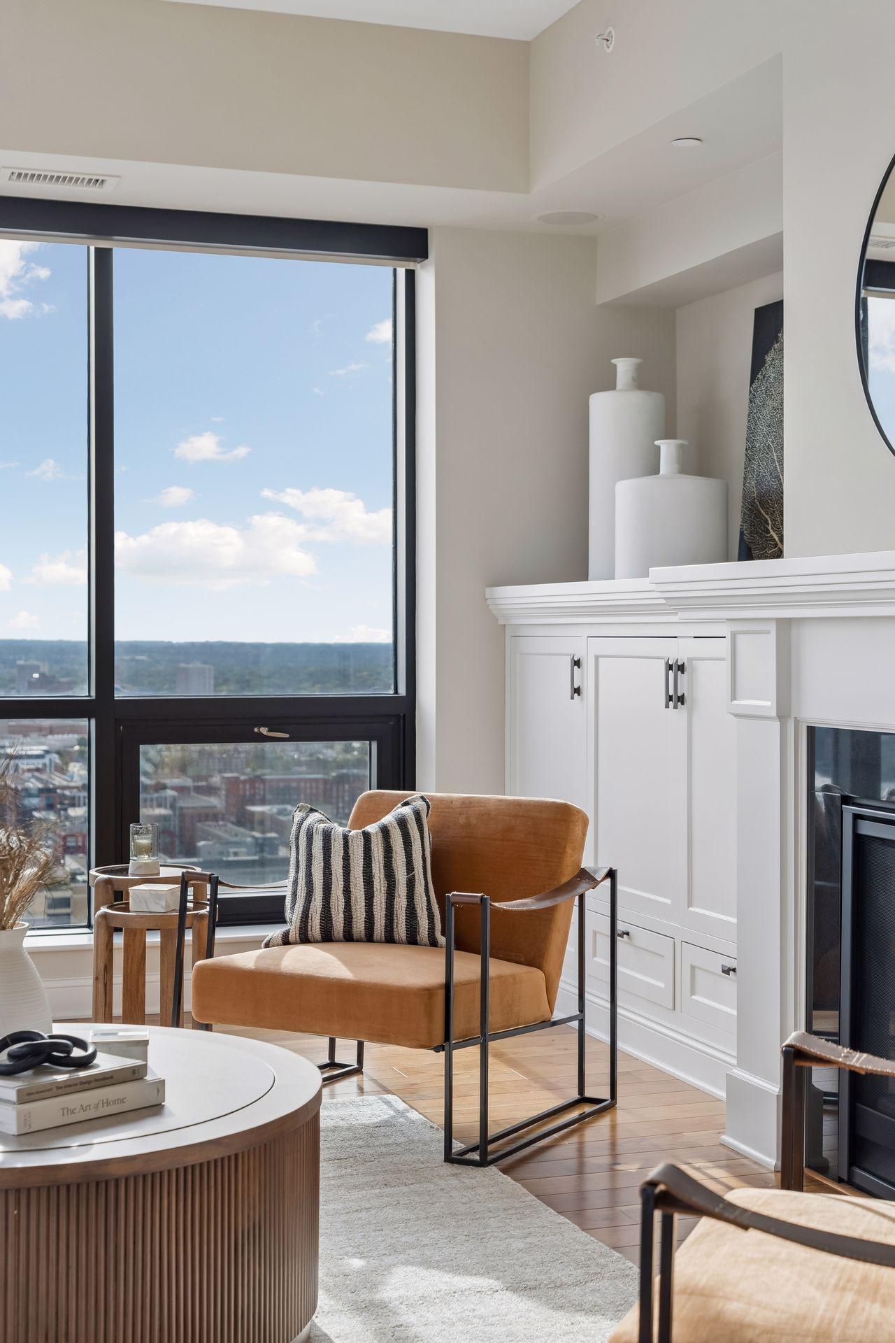 Living room with a tan leather armchair beside a large window overlooking the city.