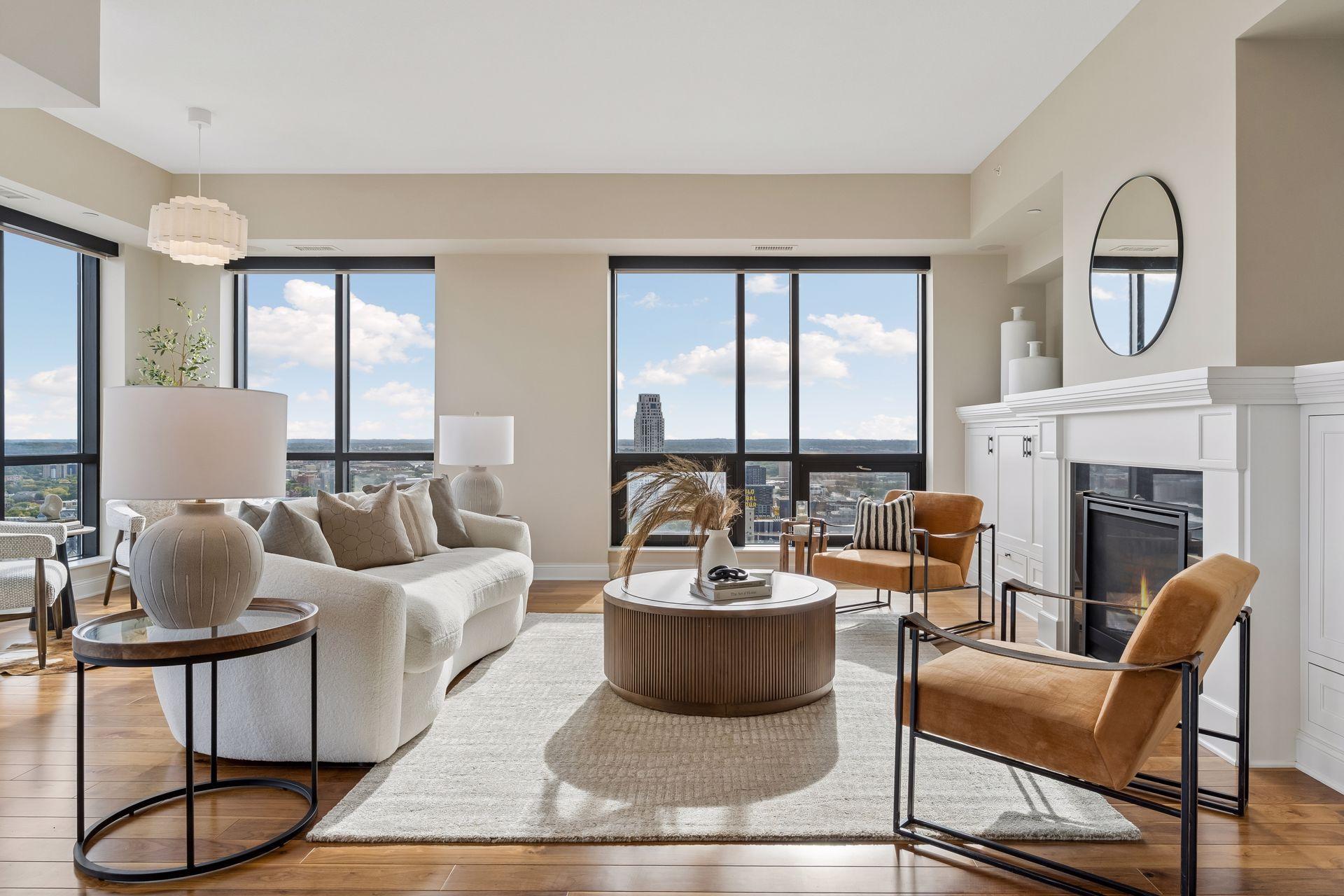 Staged condo living room with a white sofa, fireplace, and expansive windows overlooking the city.