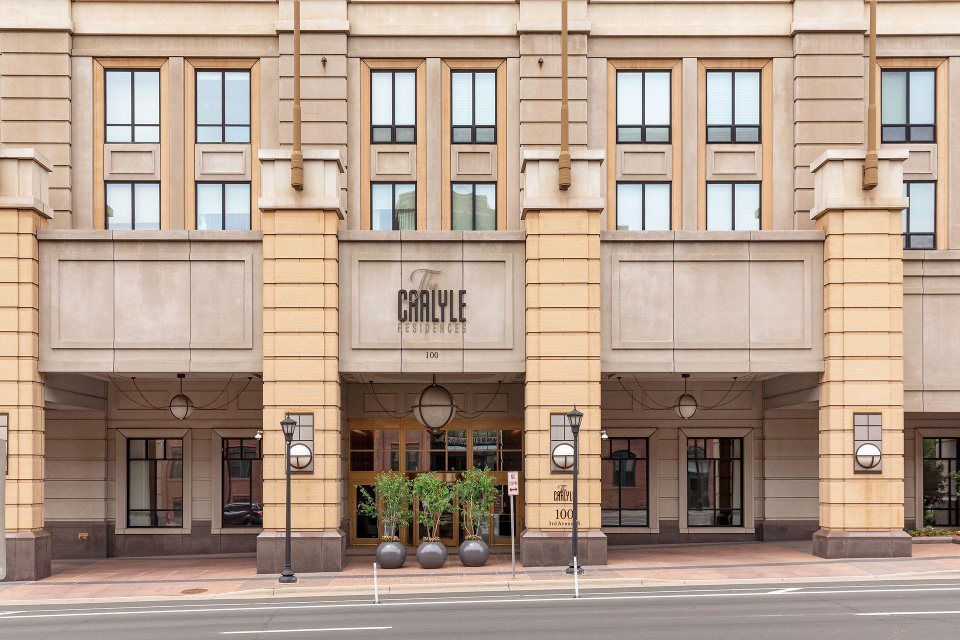 The Graylye Residences entrance, framed by beige stone columns and three round planters.