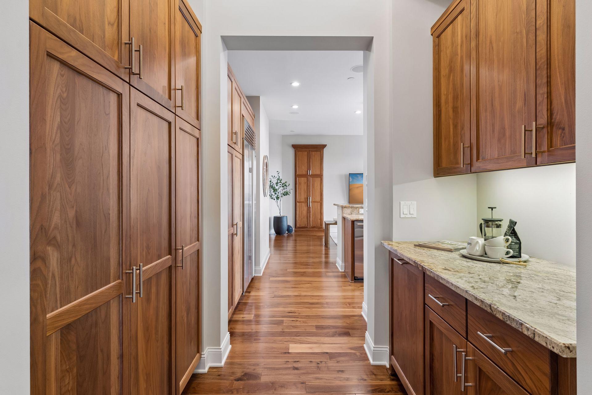 Kitchen with walnut cabinets and granite counters opening onto a hardwood hallway.