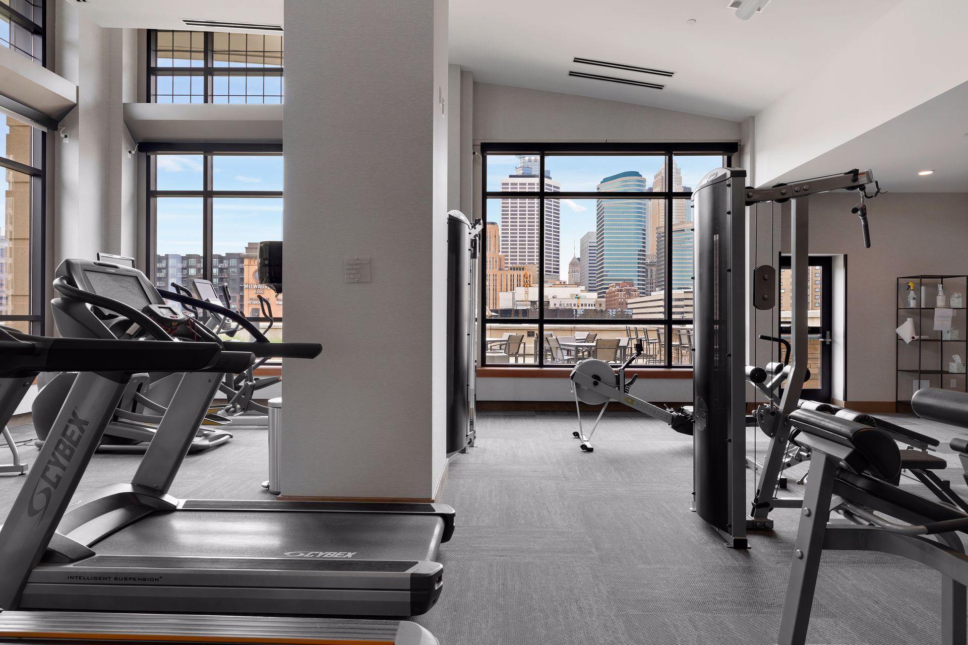 Fitness room with cardio and strength equipment and large windows overlooking the Minneapolis skyline.