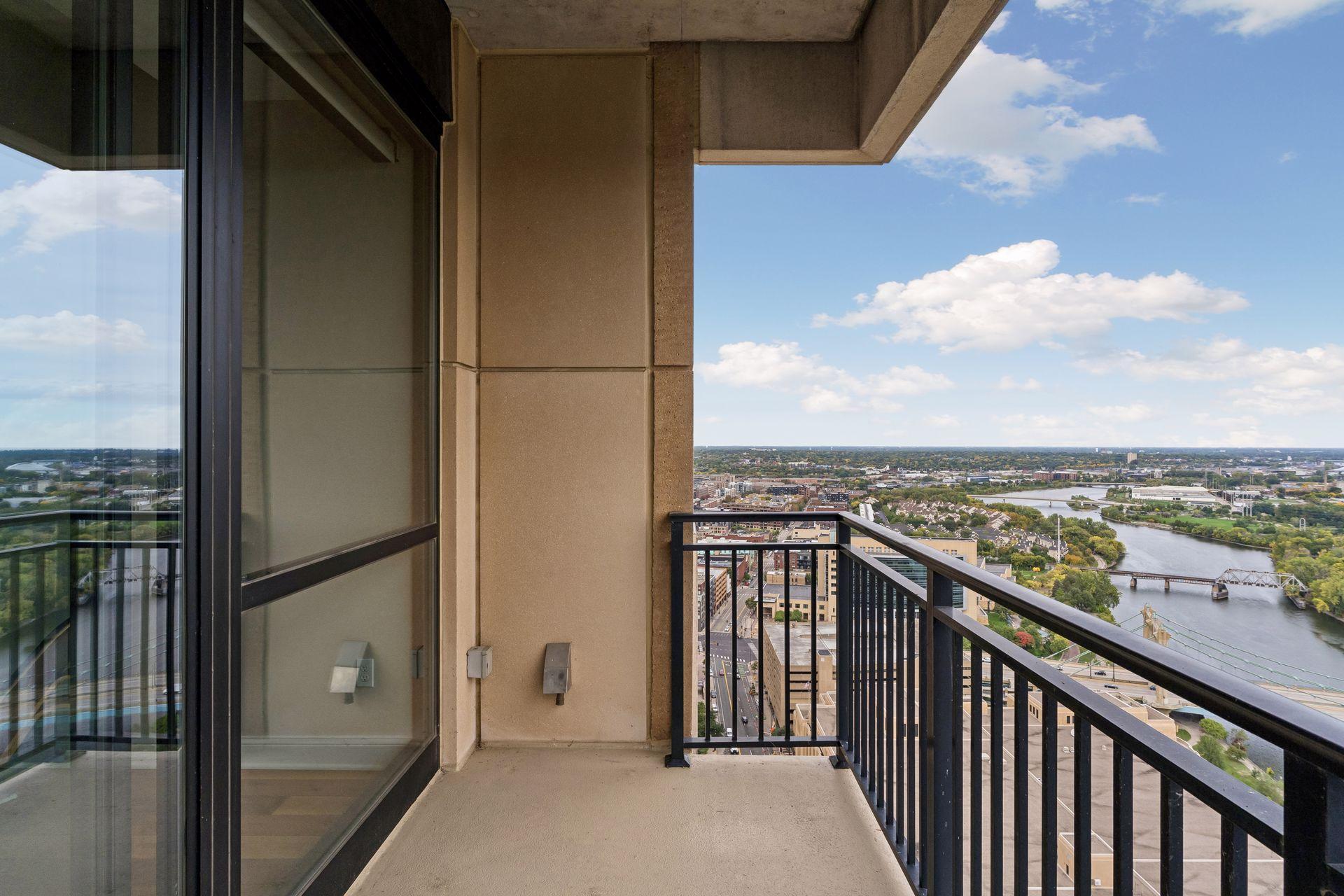 High-rise balcony overlooking a river and city with bridges in the distance.