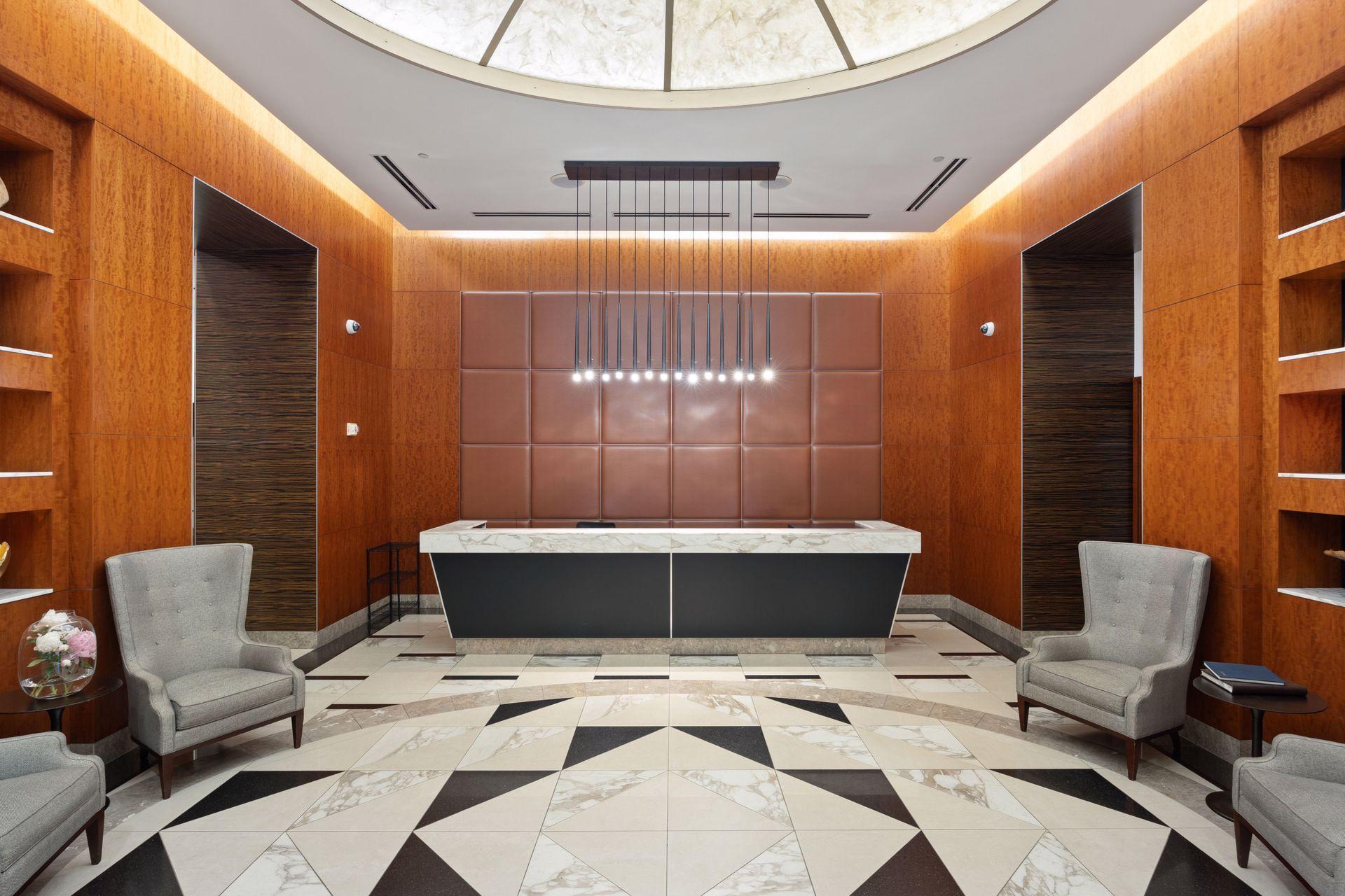 Building lobby with a marble reception desk, wood-paneled walls, and geometric marble flooring.