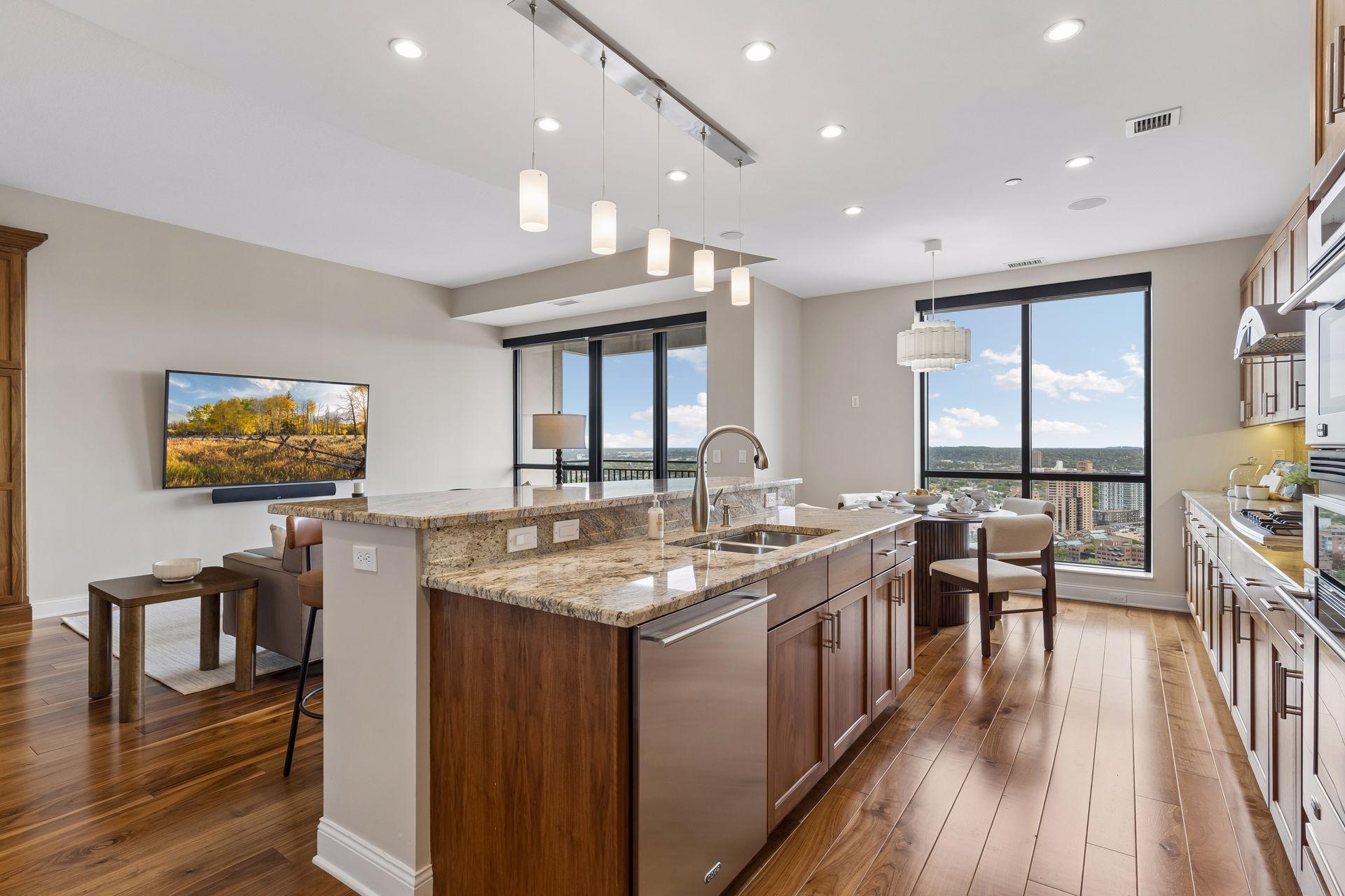 Open-plan kitchen with a granite island and floor-to-ceiling windows overlooking the city.