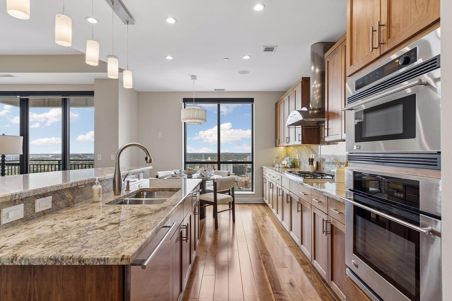 High-rise condo kitchen with granite island, wood cabinets, stainless appliances, and city views.