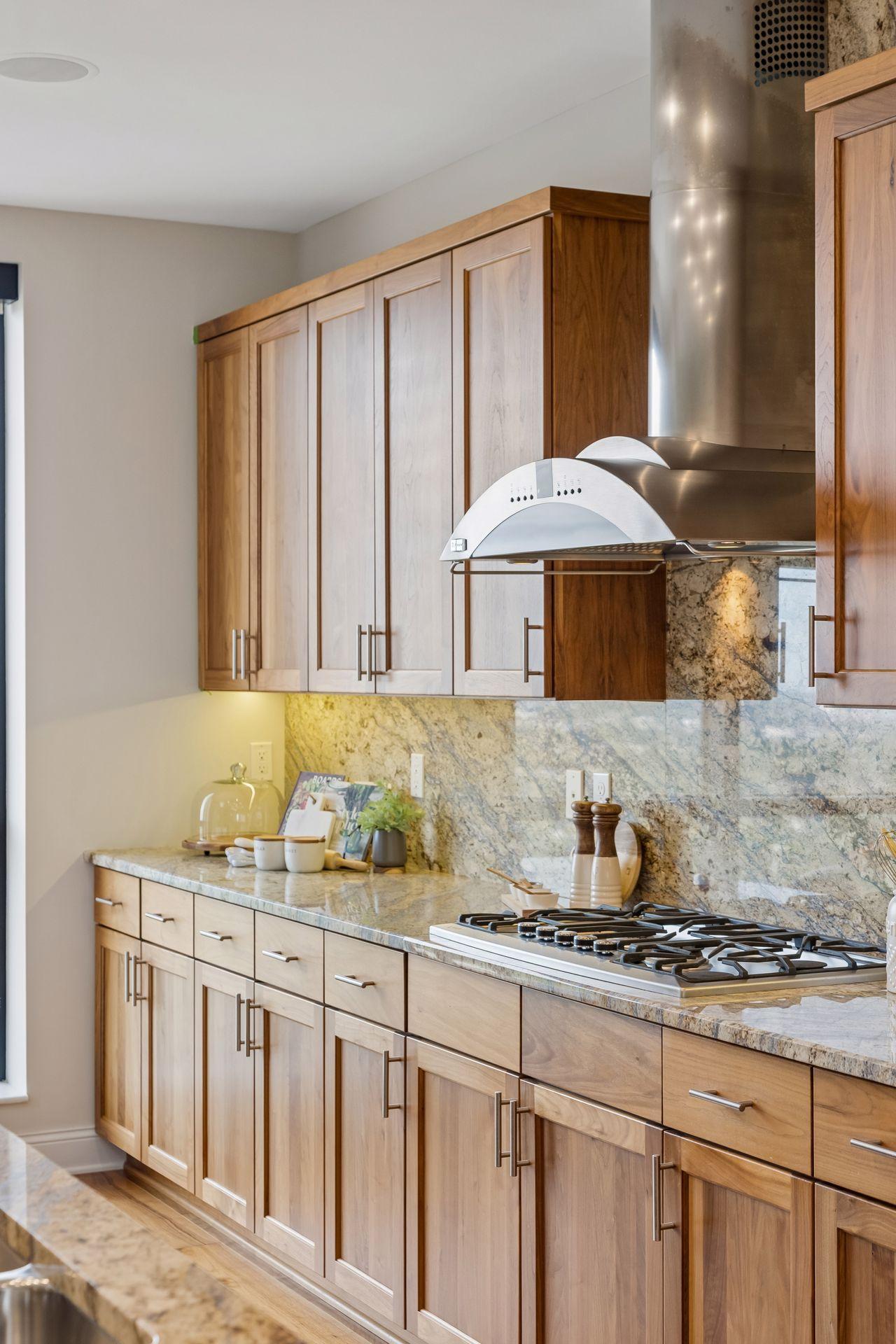 Condo kitchen with two-tone wood cabinets, veined stone counters, and a stainless steel gas cooktop.