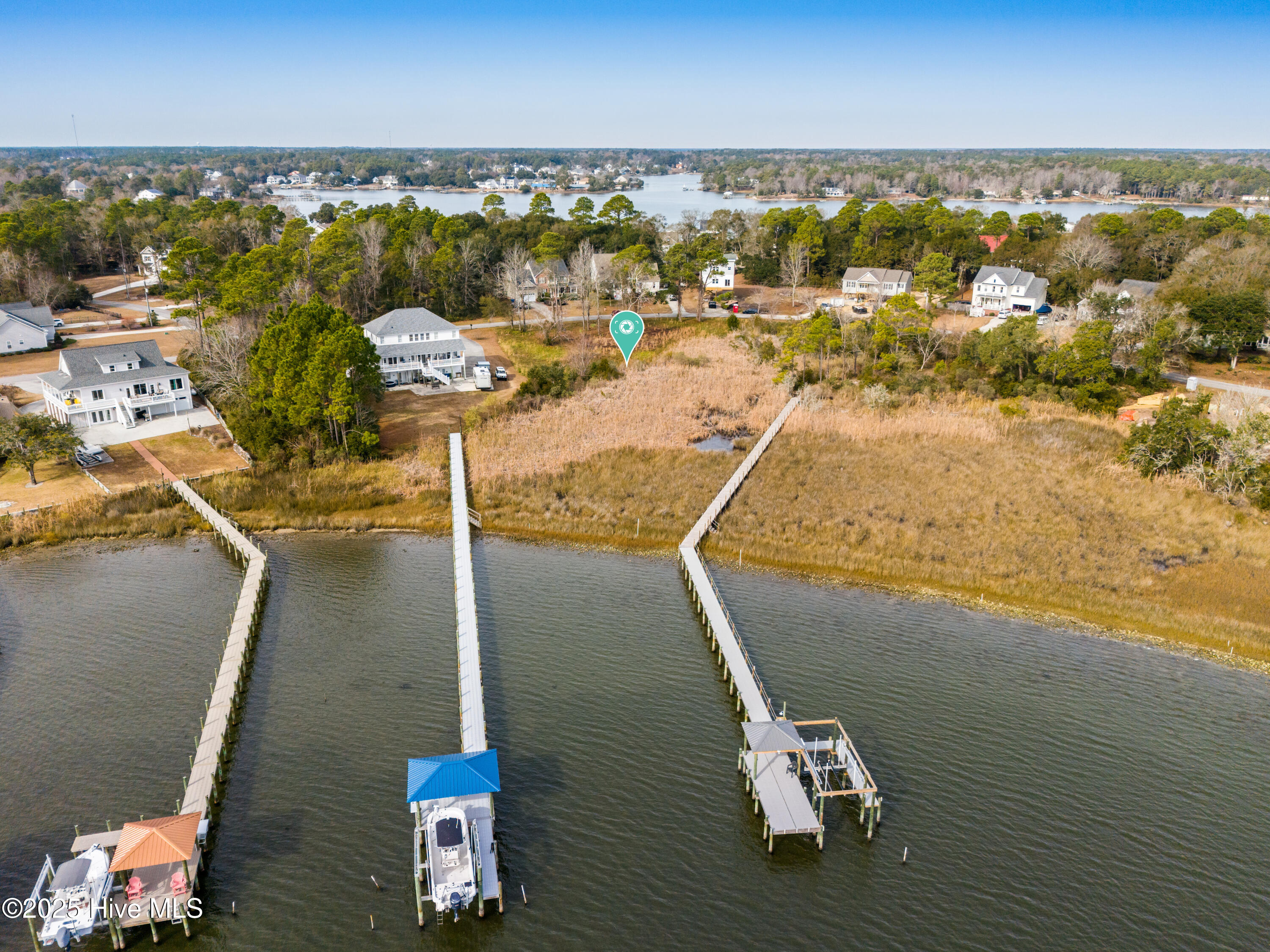 Aerial view of a waterfront lot with marsh grass and long docks extending into the water.