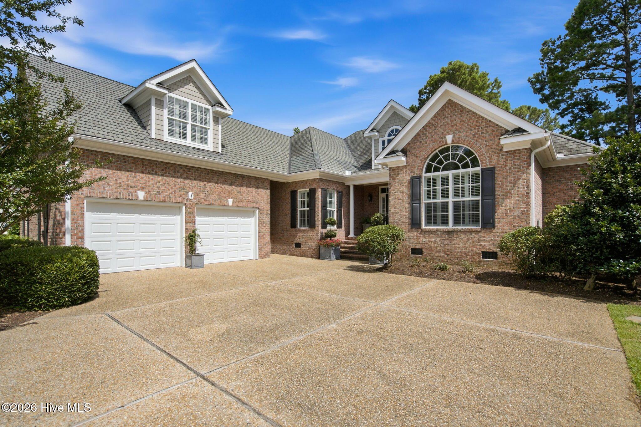 Brick house with an arched front window, two-car garage, and wide driveway.