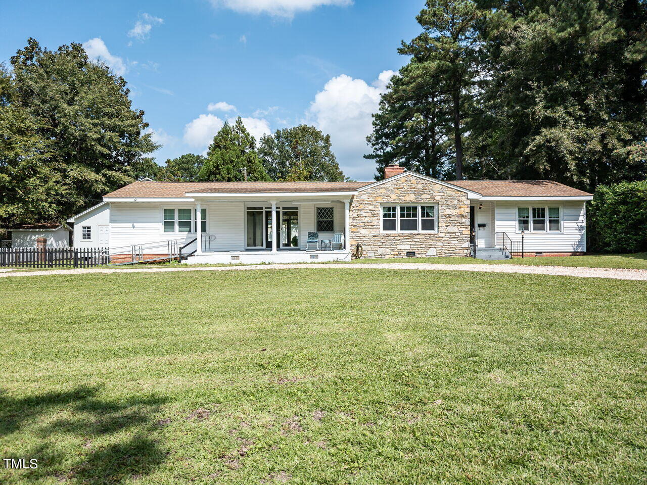 Single-story white house with a central stone facade, covered porch, and broad front lawn.