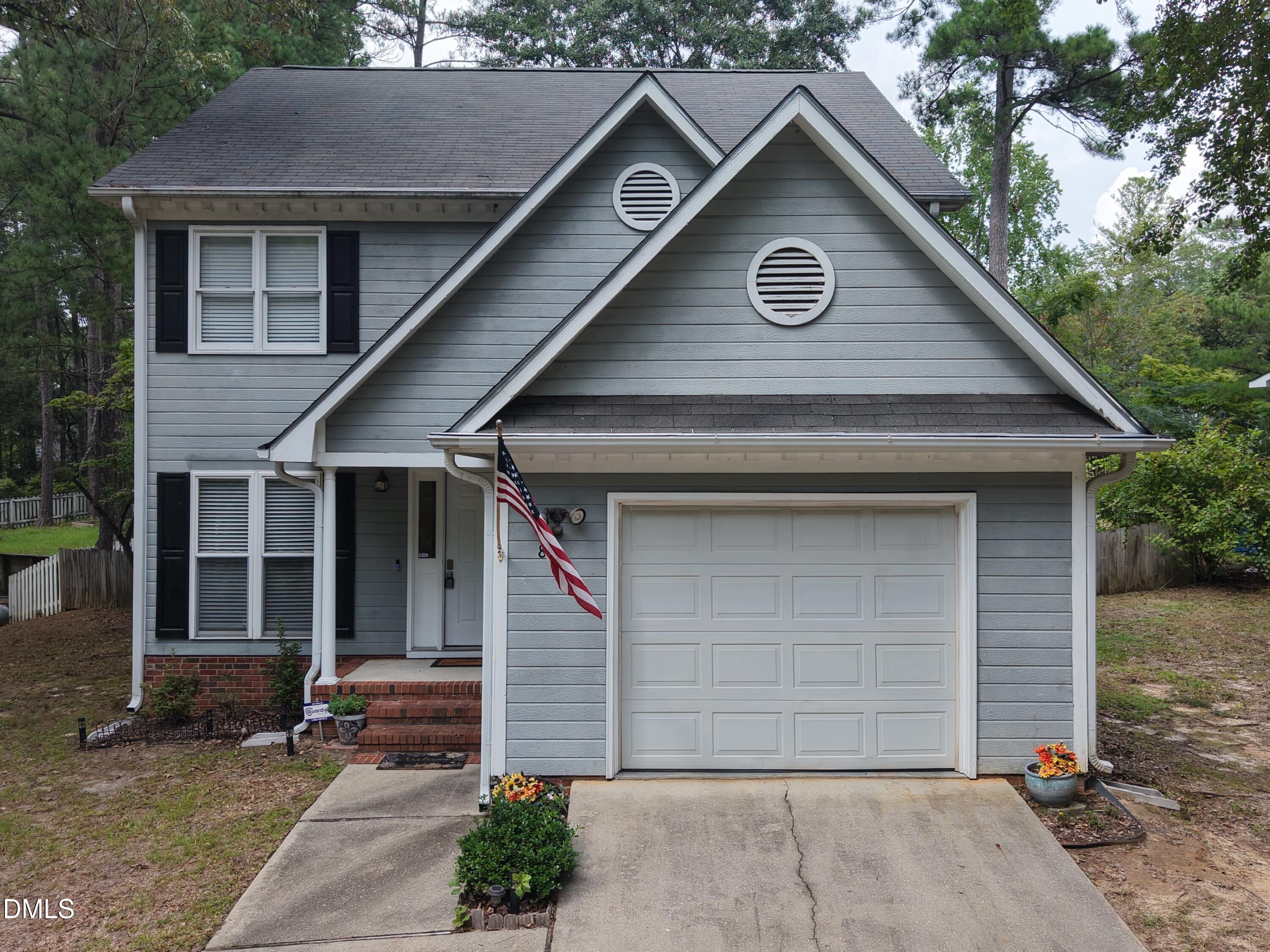Gray two-story house with steep gables, a double garage, brick steps, and an American flag.