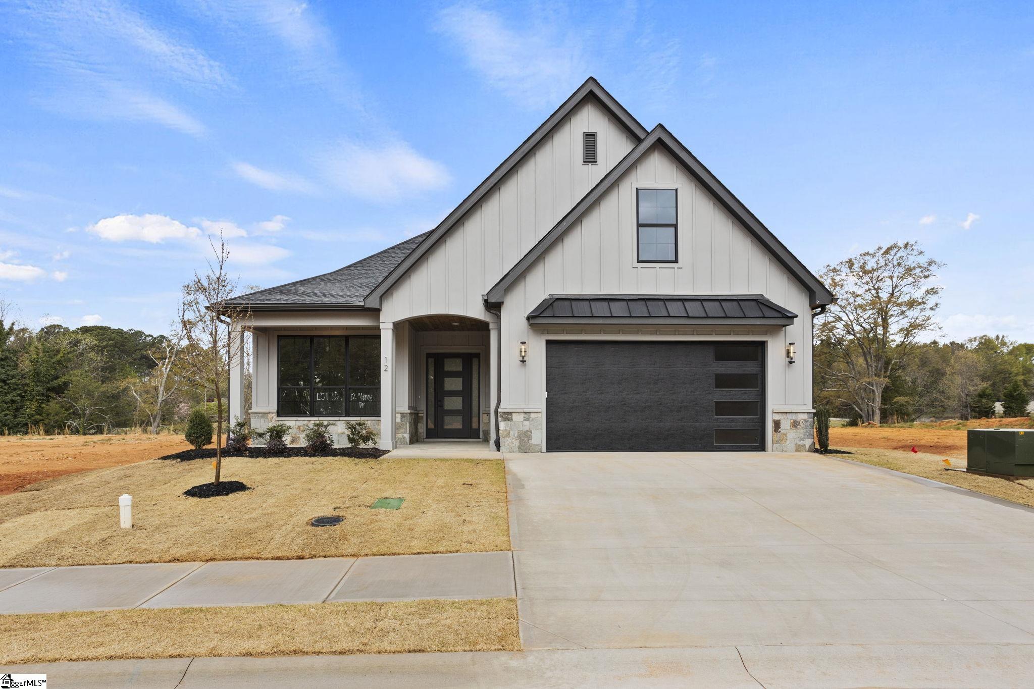 White gabled home with dark trim, stone accents, and a wide driveway.