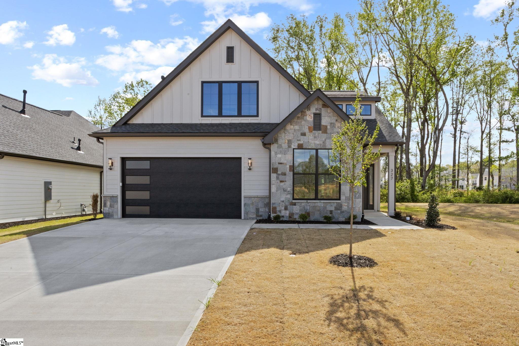 Modern two-story home with a stone-accented entrance, black garage door, and wide driveway.
