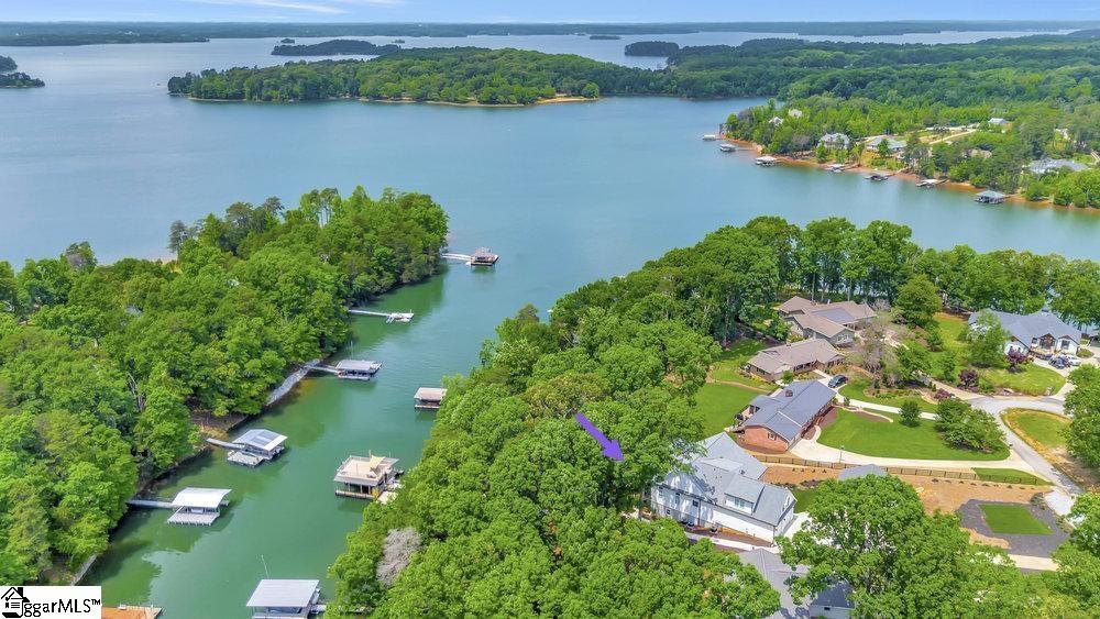 Aerial view of a lakefront neighborhood, with a purple arrow marking a white house.