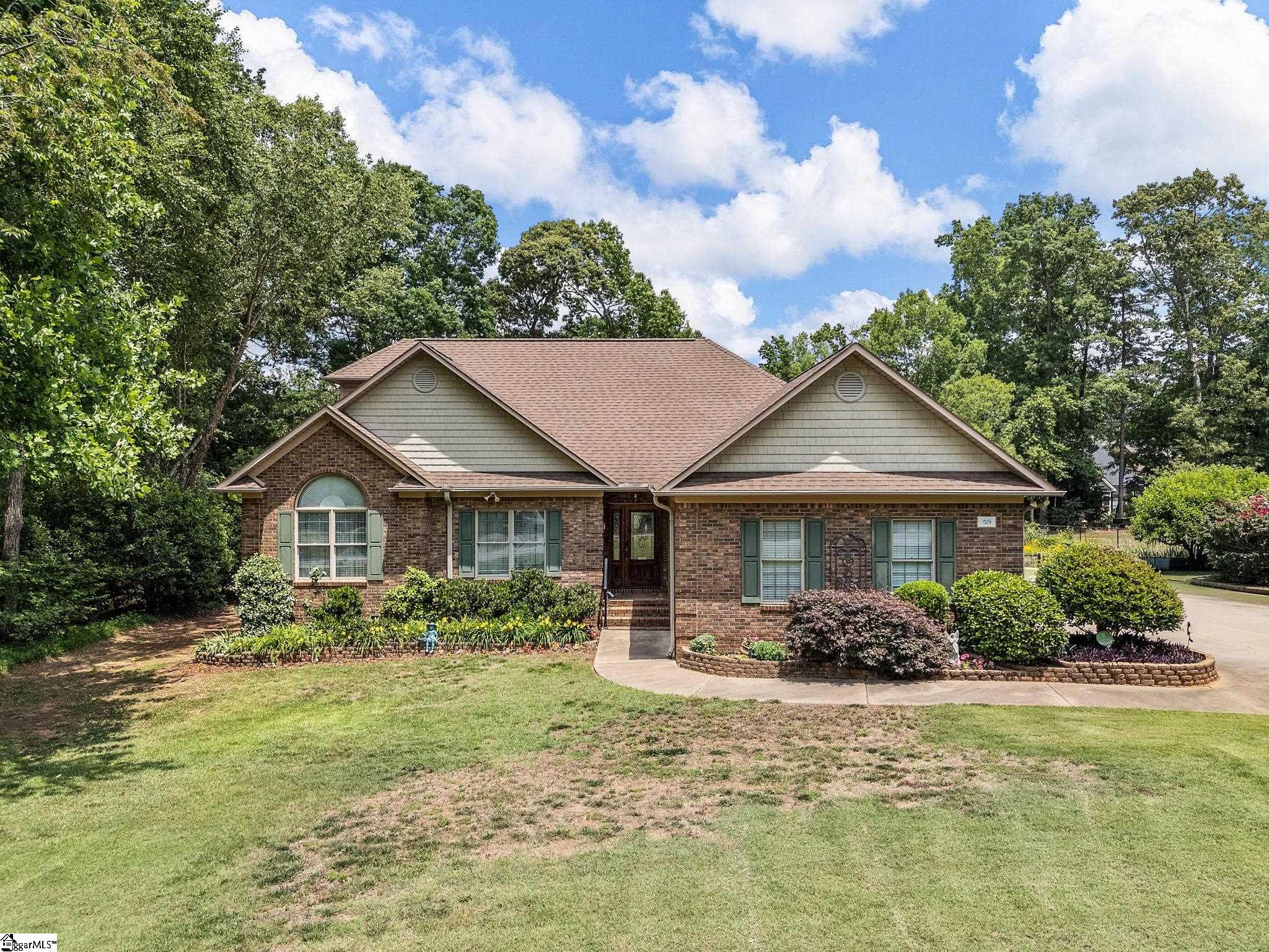 Brick-and-siding home with green shutters, landscaped beds, and a broad front lawn.