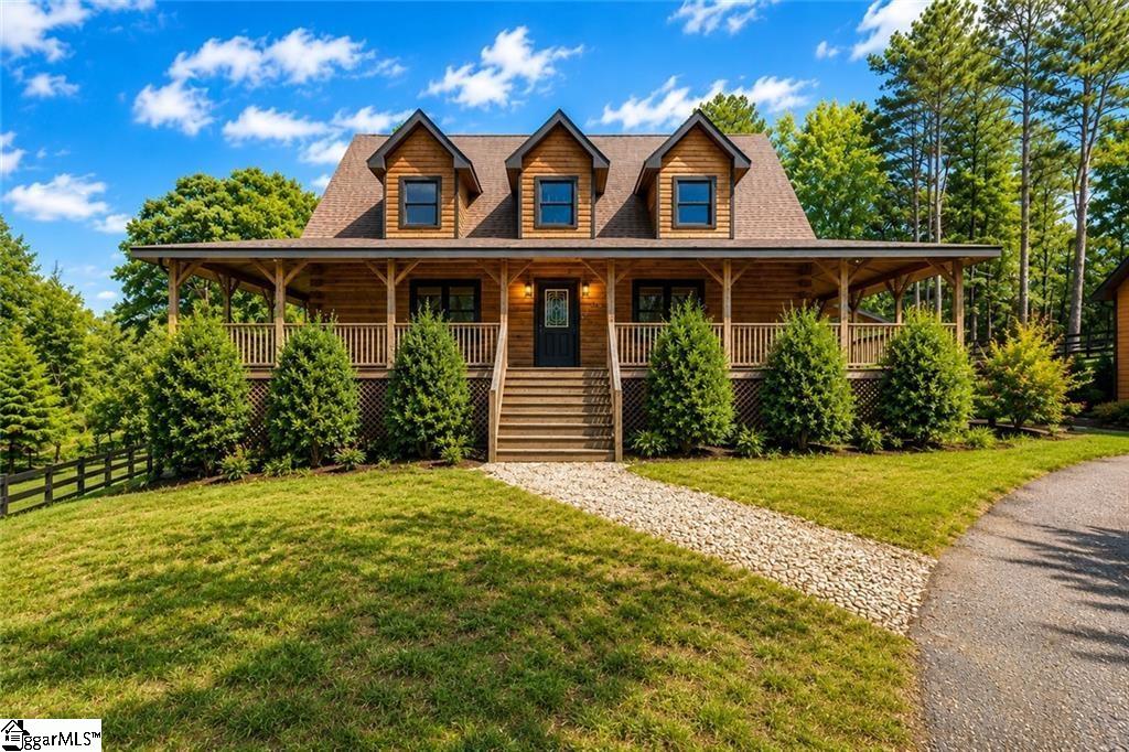 Timber-style home with three dormers, a covered porch, and a stone walkway.