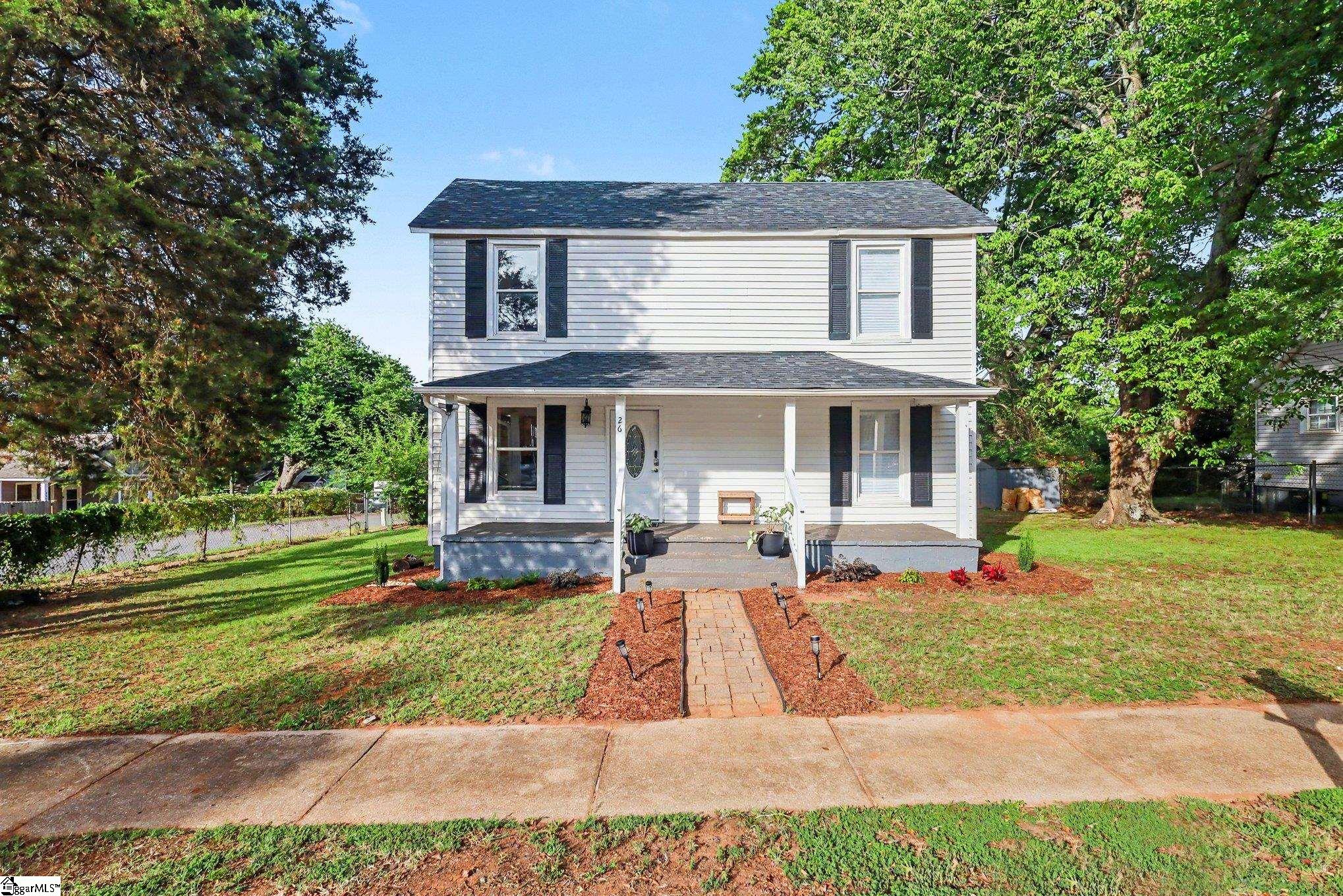 Two-story house with dark shutters, a covered porch, and a brick walkway through the front lawn.