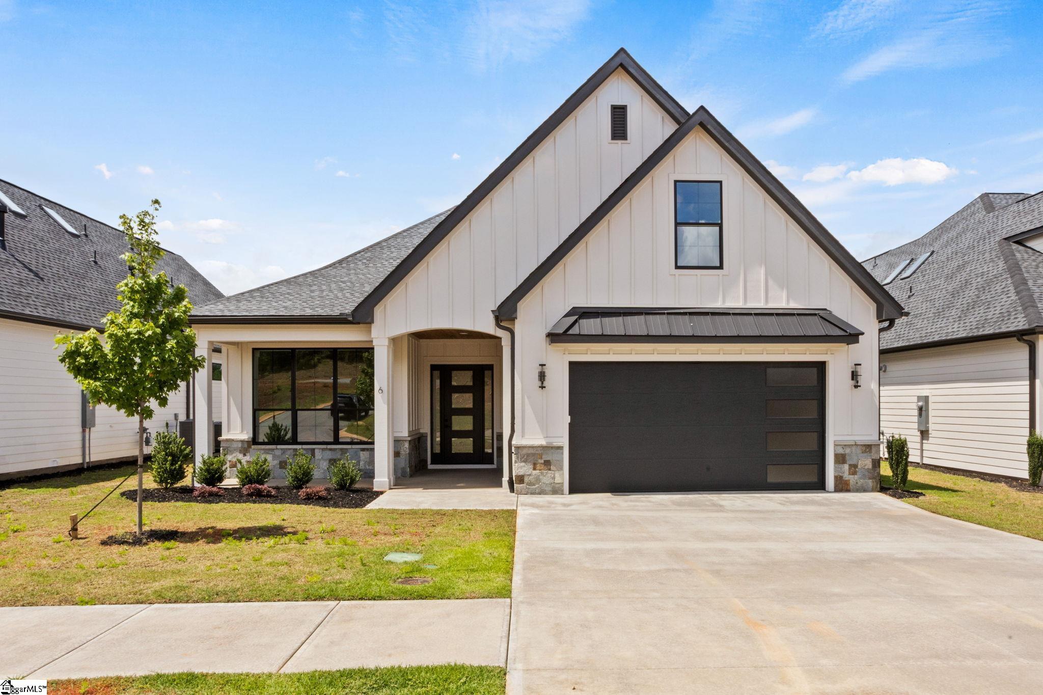 White modern home with intersecting gables, dark trim, and a double garage.