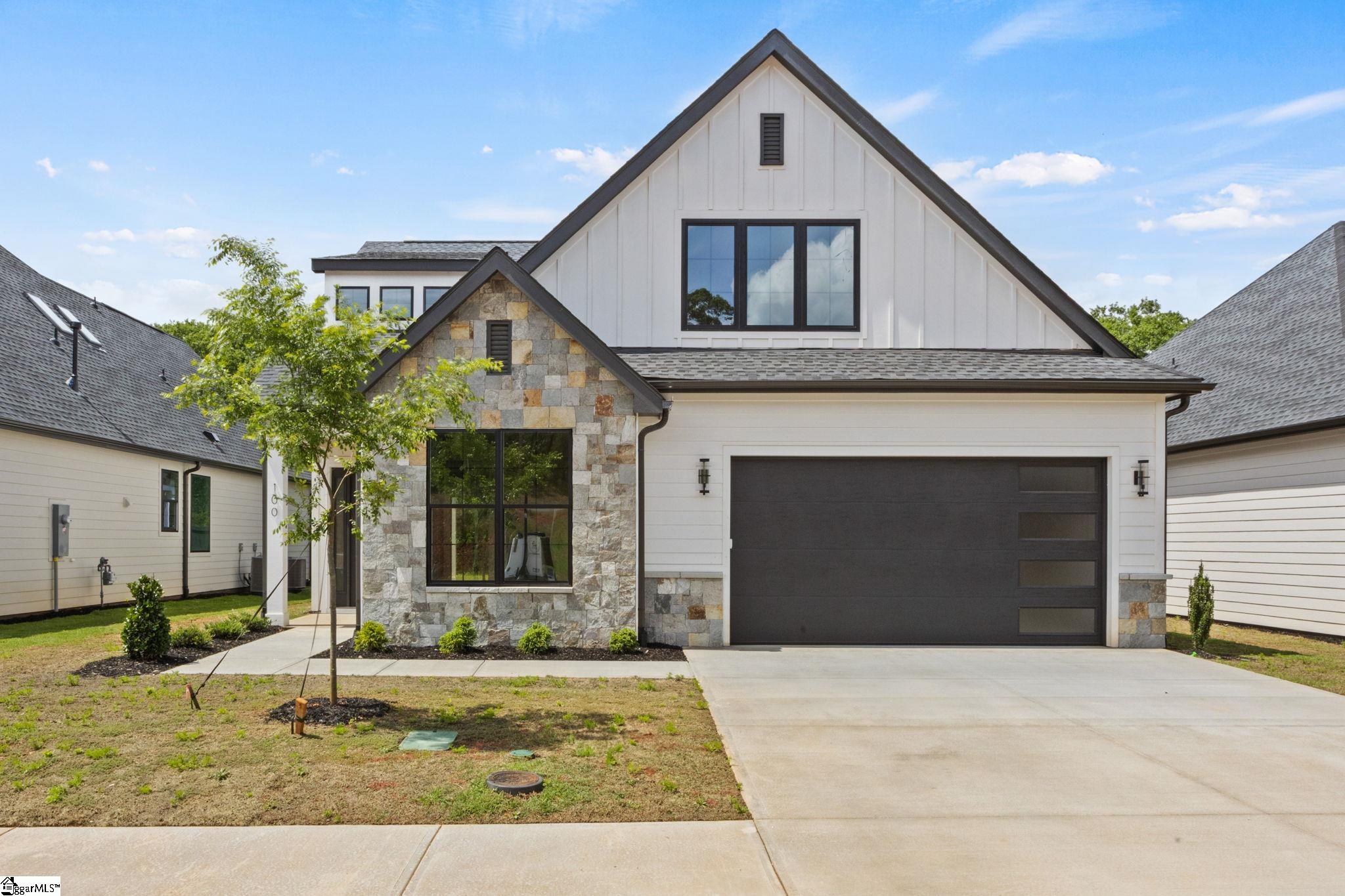 Modern white two-story home with a stone-clad entry, steep gables, and a dark double garage door.