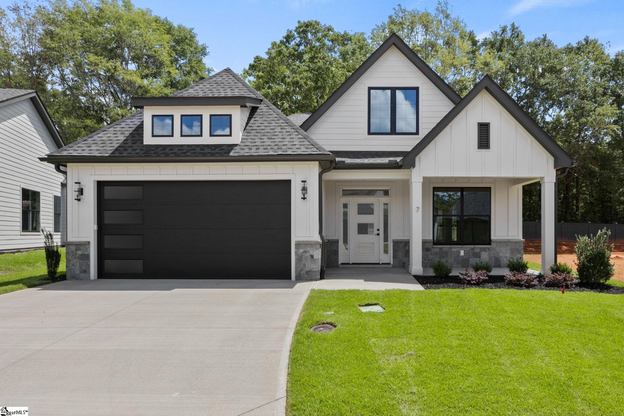 White gabled home with a dark double garage, stone accents, and a covered entry.