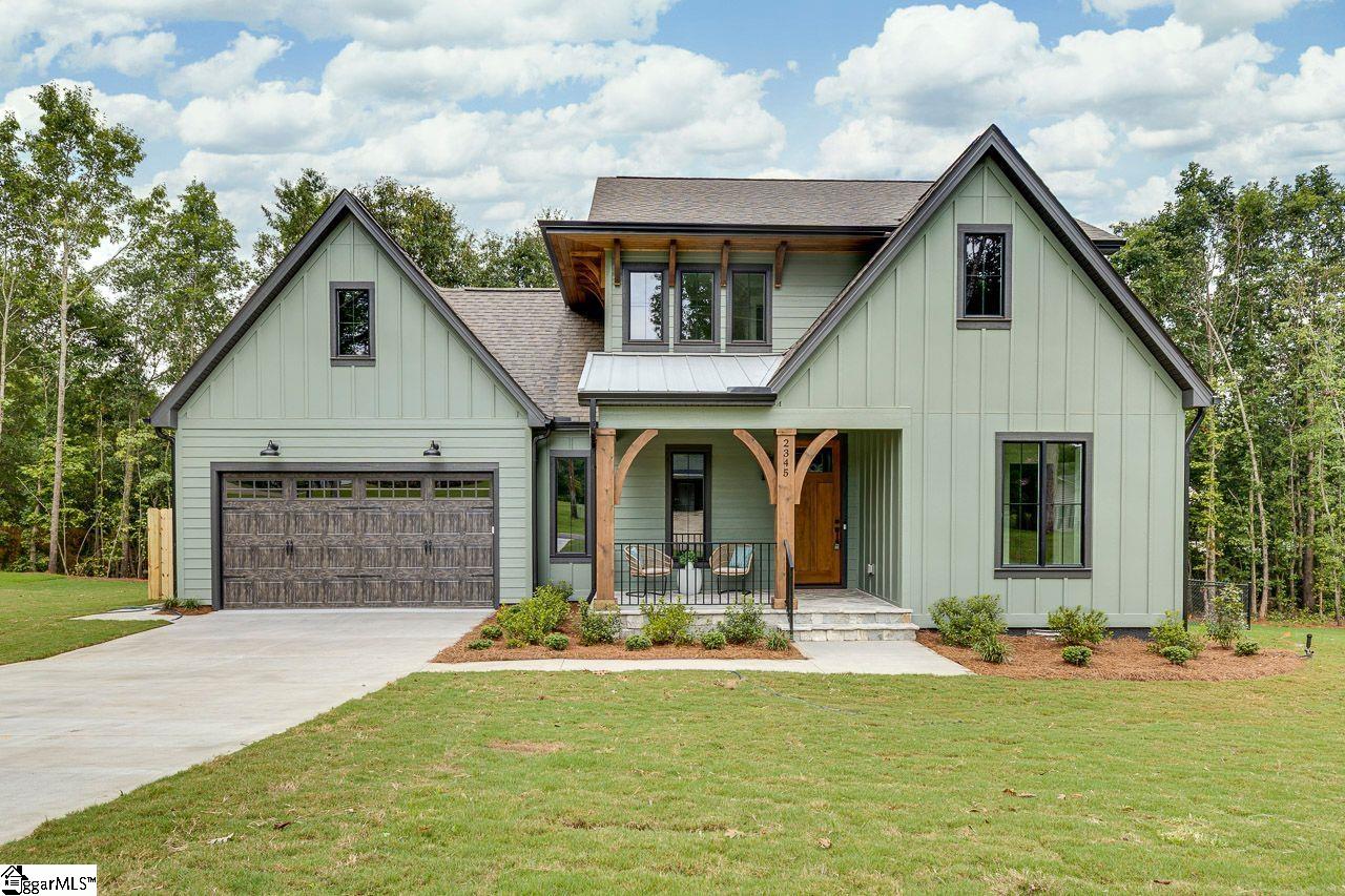 Pale green home with prominent gables, a two-car garage, and a covered front porch.