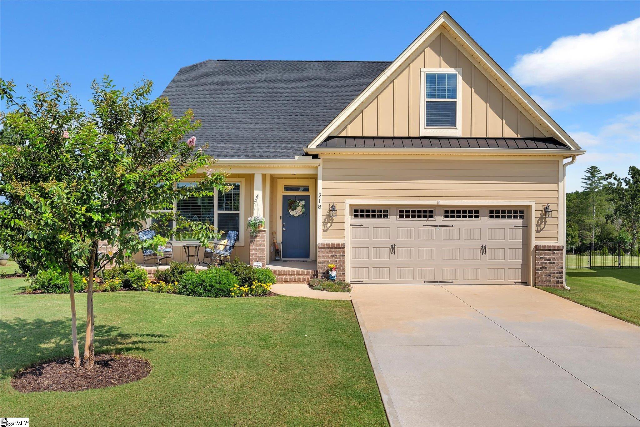 Beige two-story home with a blue front door, double garage, landscaped lawn, and wide driveway.