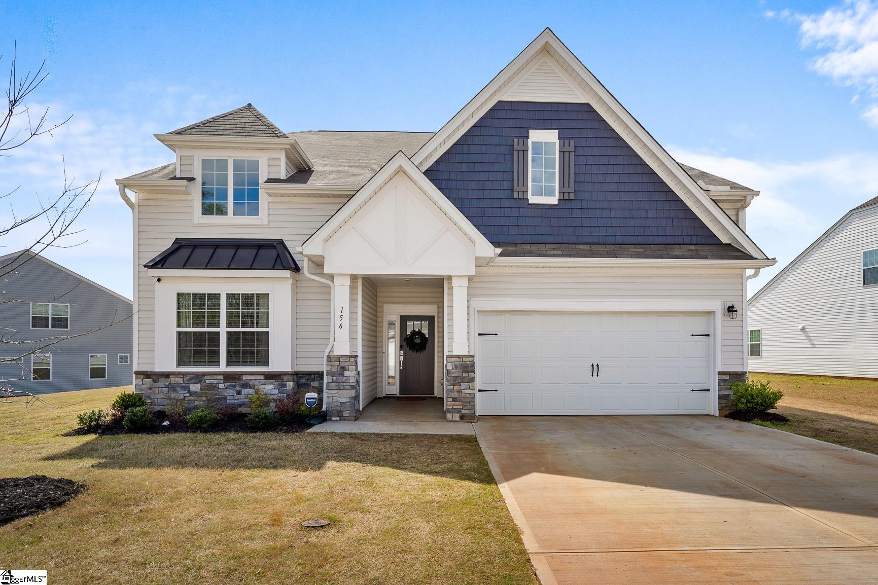 Two-story light-sided home with a dark blue gable, stone accents, and an attached double garage.