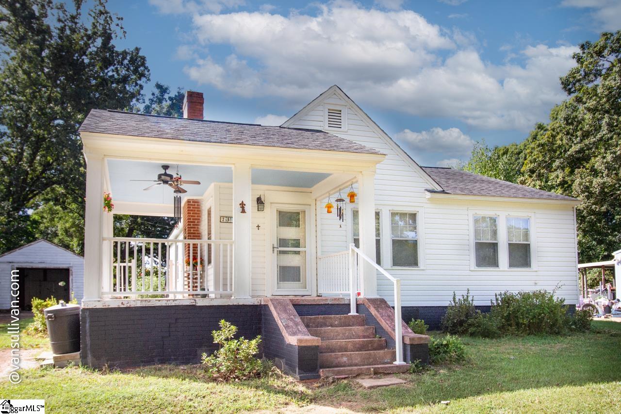 White house with a covered porch, white railings, and brick steps.