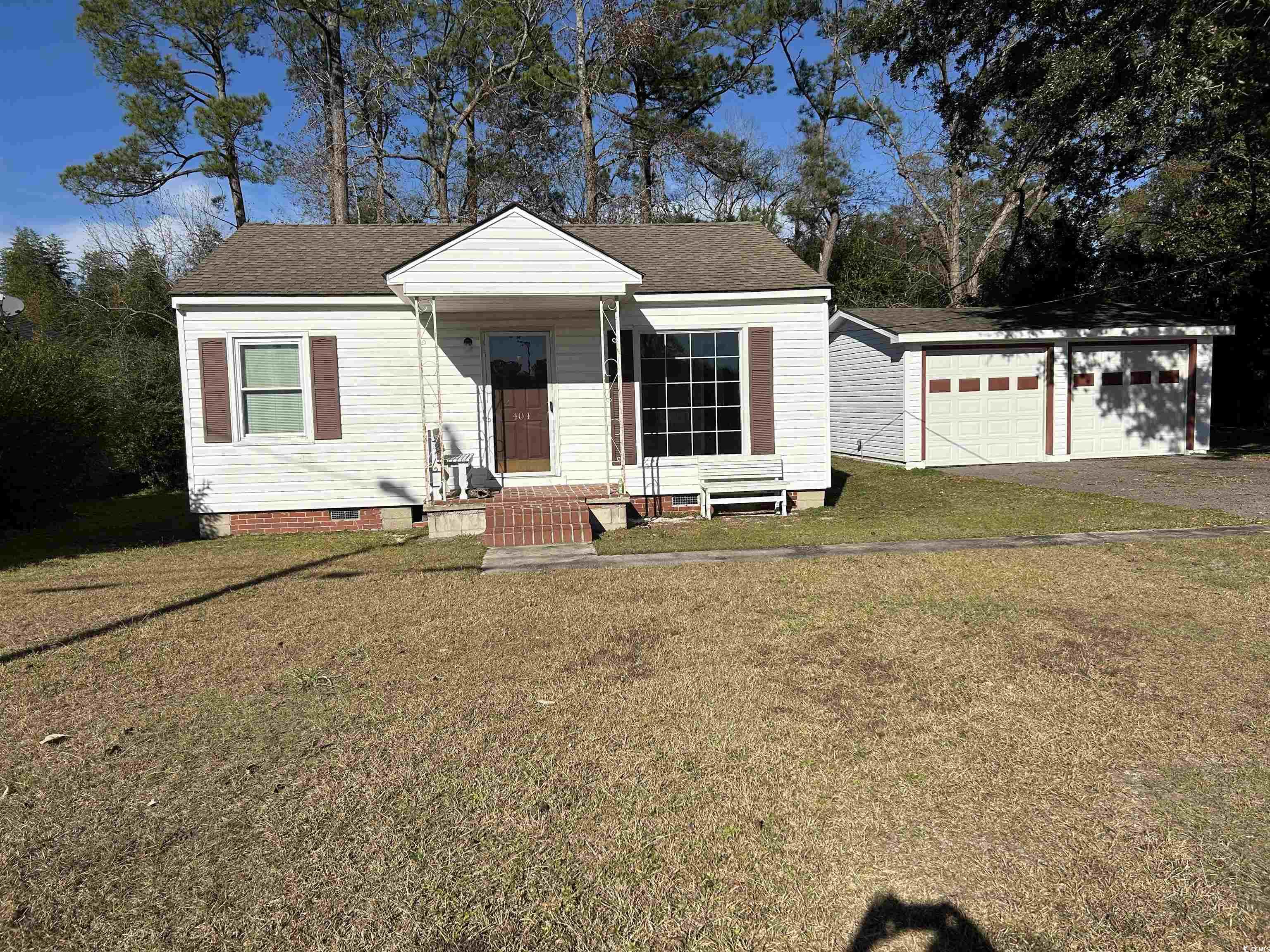 White single-story house with brown shutters, brick entry steps, and a double garage.