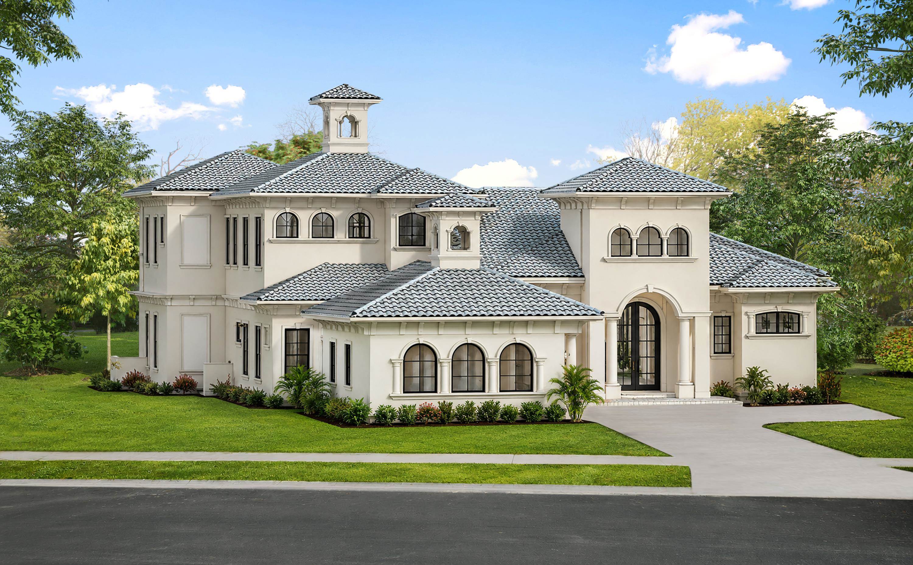 Large cream-colored house with tiled roofs, arched windows, landscaped lawn, and wide driveway.
