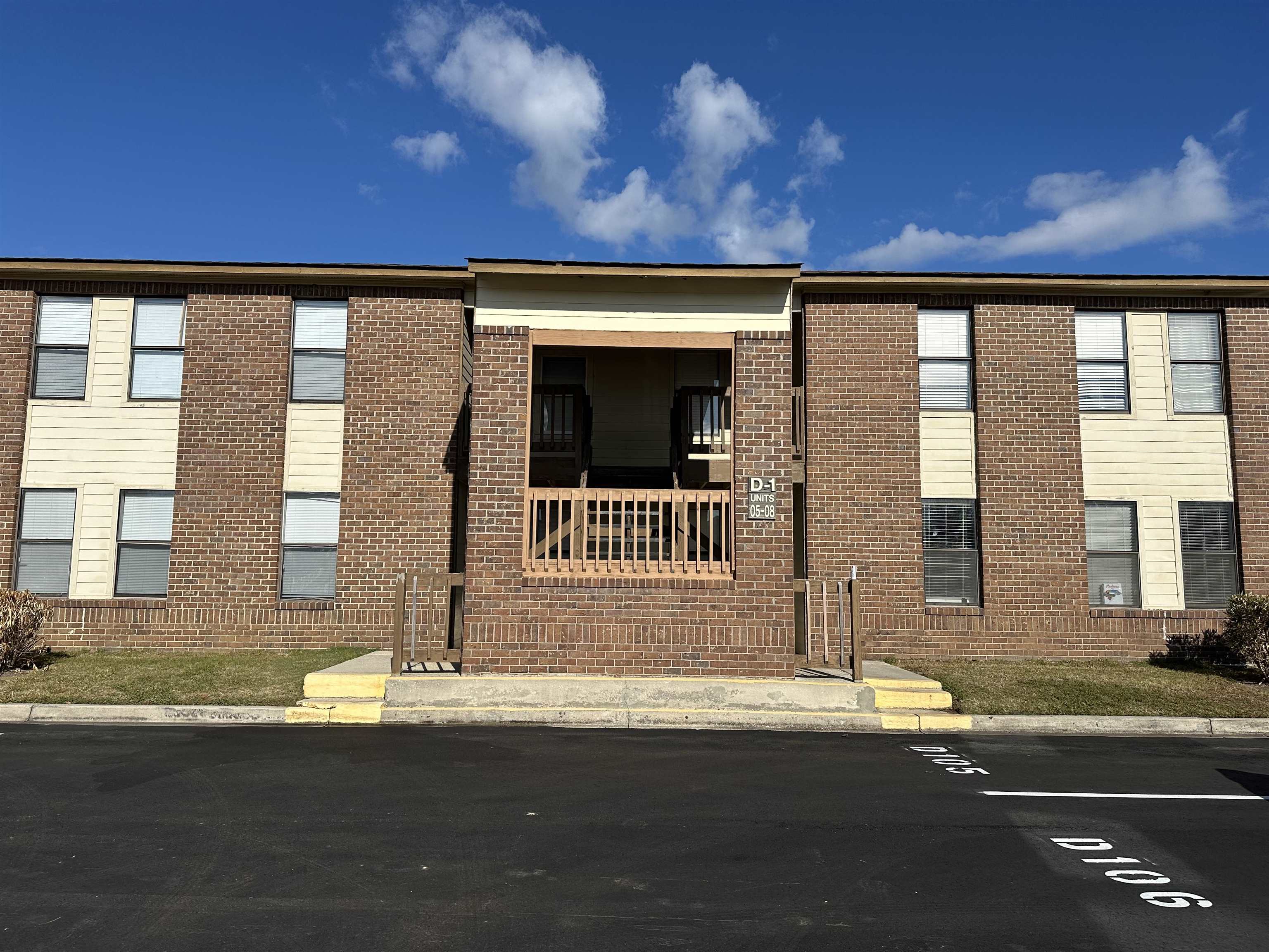 Two-story brick apartment building with a central covered entrance and balcony.
