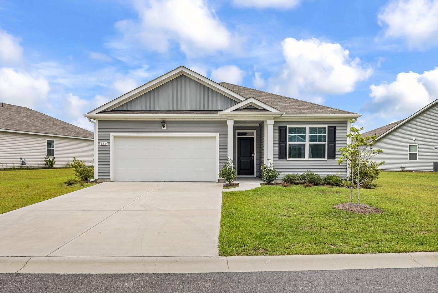 Gray single-story home with a double garage, covered entry, and broad concrete driveway.