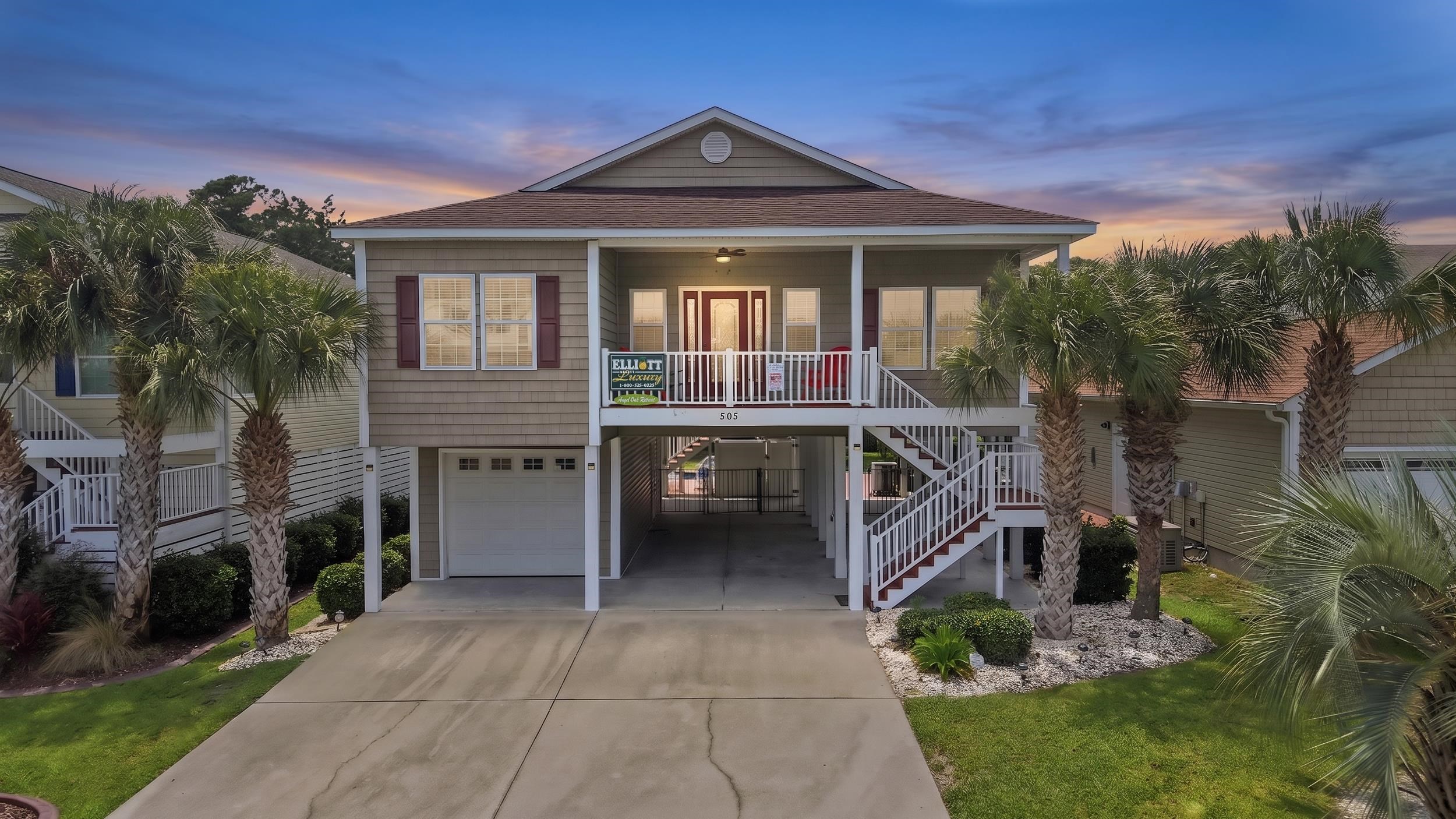 Raised coastal home with a covered porch, white stairs, palm trees, and parking beneath the house.