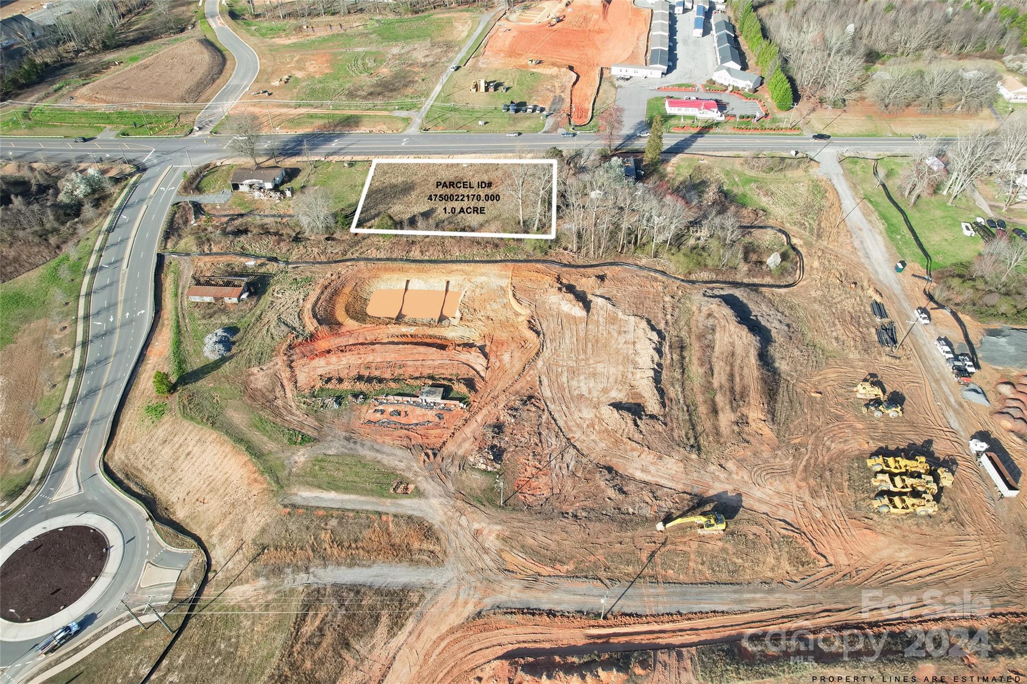 One-acre parcel outlined beside a road, surrounded by an active construction site.