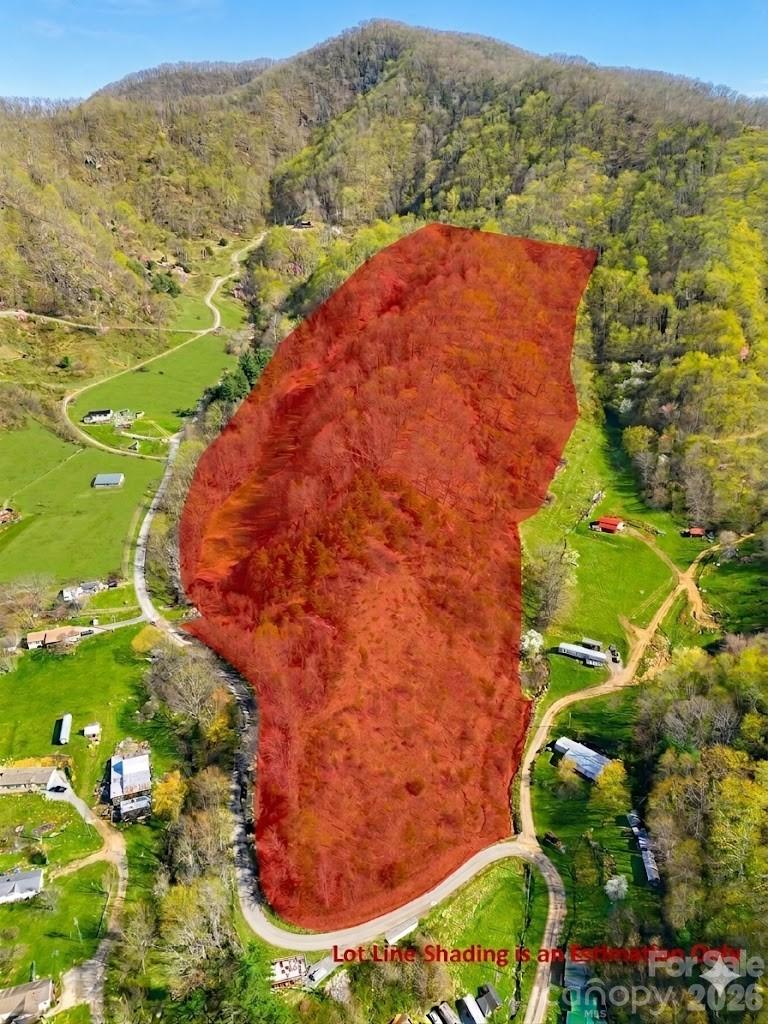 Aerial view of a wooded mountain parcel outlined in red, with a winding access road.