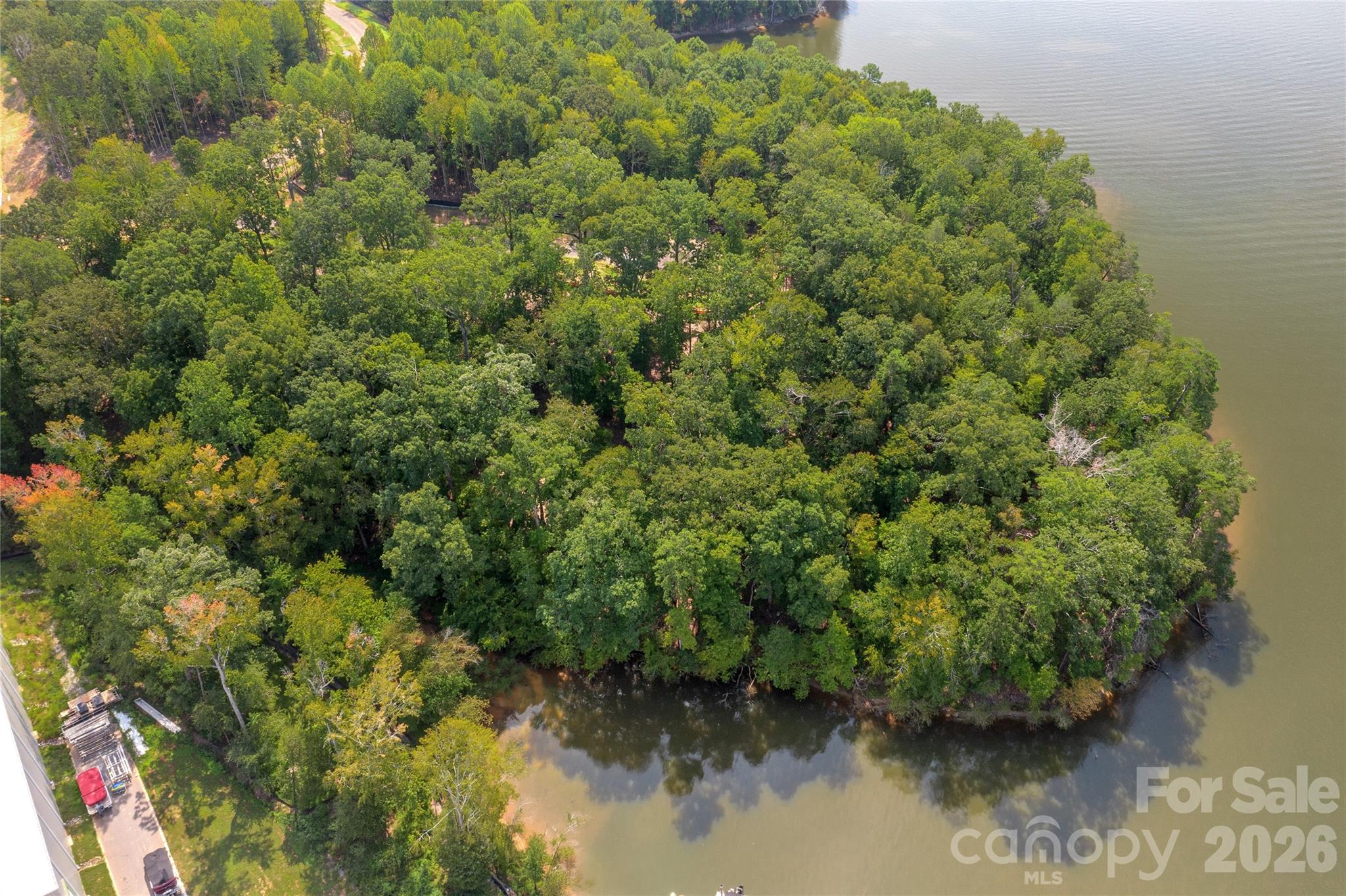 Aerial view of wooded land extending to a river shoreline.