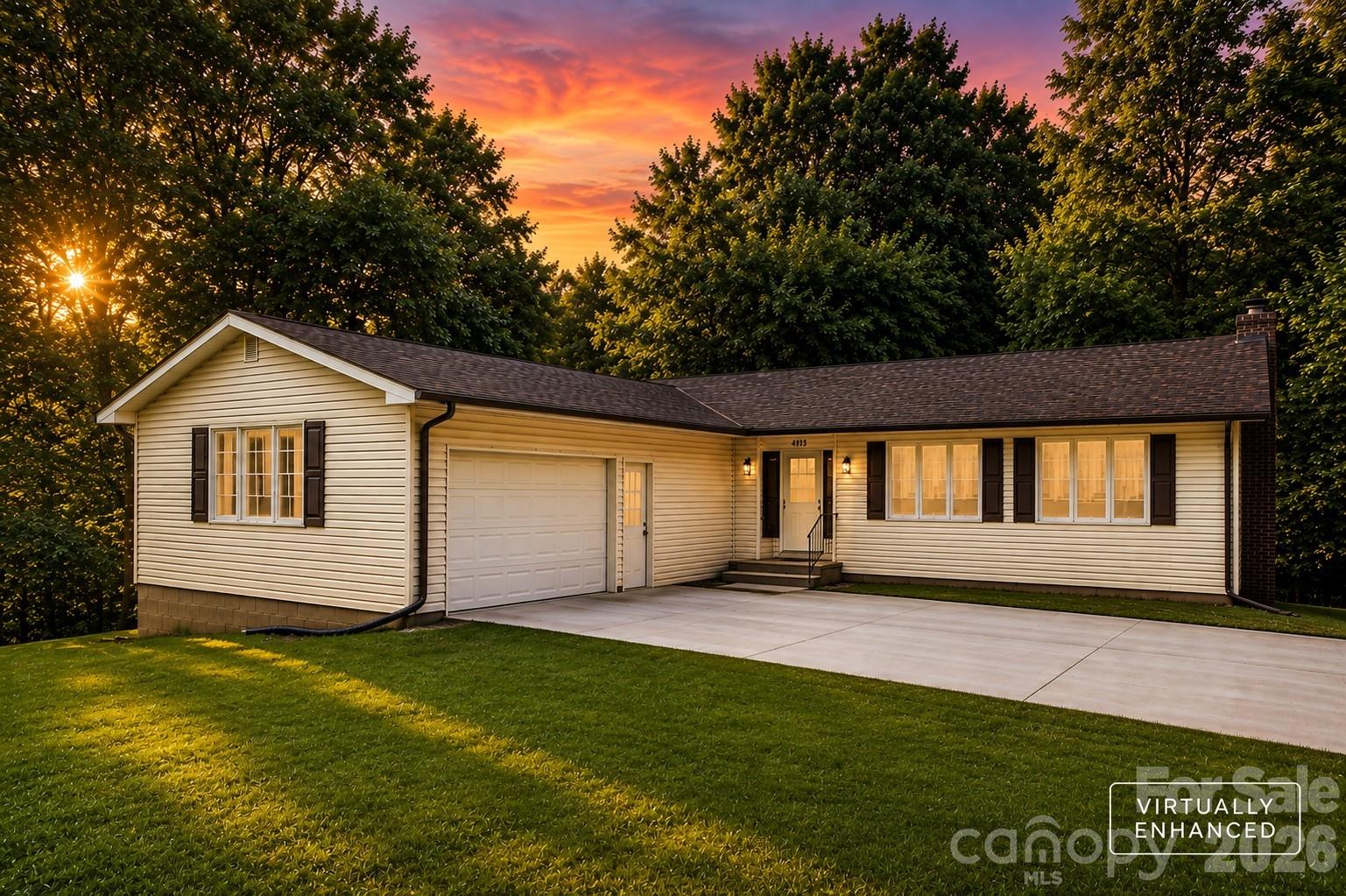 Single-story home with attached garage and broad driveway beneath a vivid sunset sky.