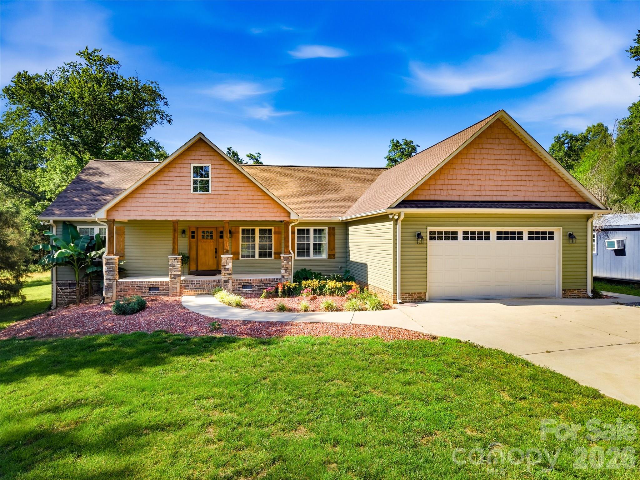 Home with peach gables, a covered porch, attached two-car garage, and landscaped front lawn.