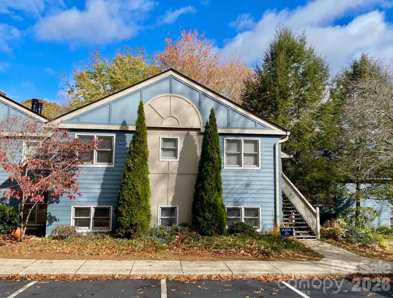 Blue-sided building with a peaked roof, central arched feature, and exterior staircase.