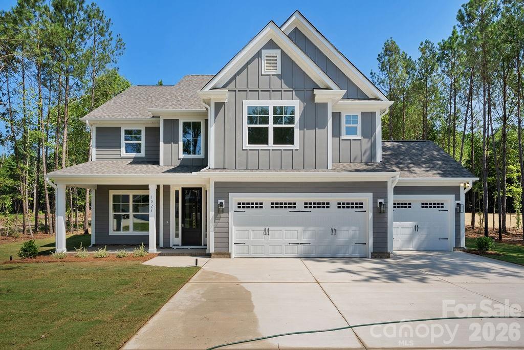 Gray two-story home with prominent gables, a three-car garage, and a wide concrete driveway.